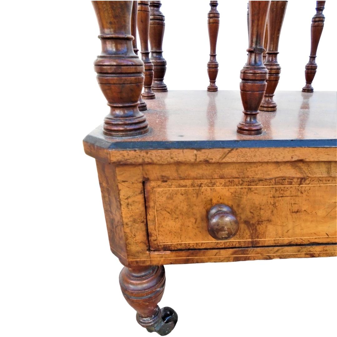 English walnut and satinwood inlay and ebonite’s Canterbury newspaper/book rack; early Victorian circa 1860; Molded top frame with uprights to each corner; topped with finials; two divisions with turned spindles; single drawer; slender turned legs
