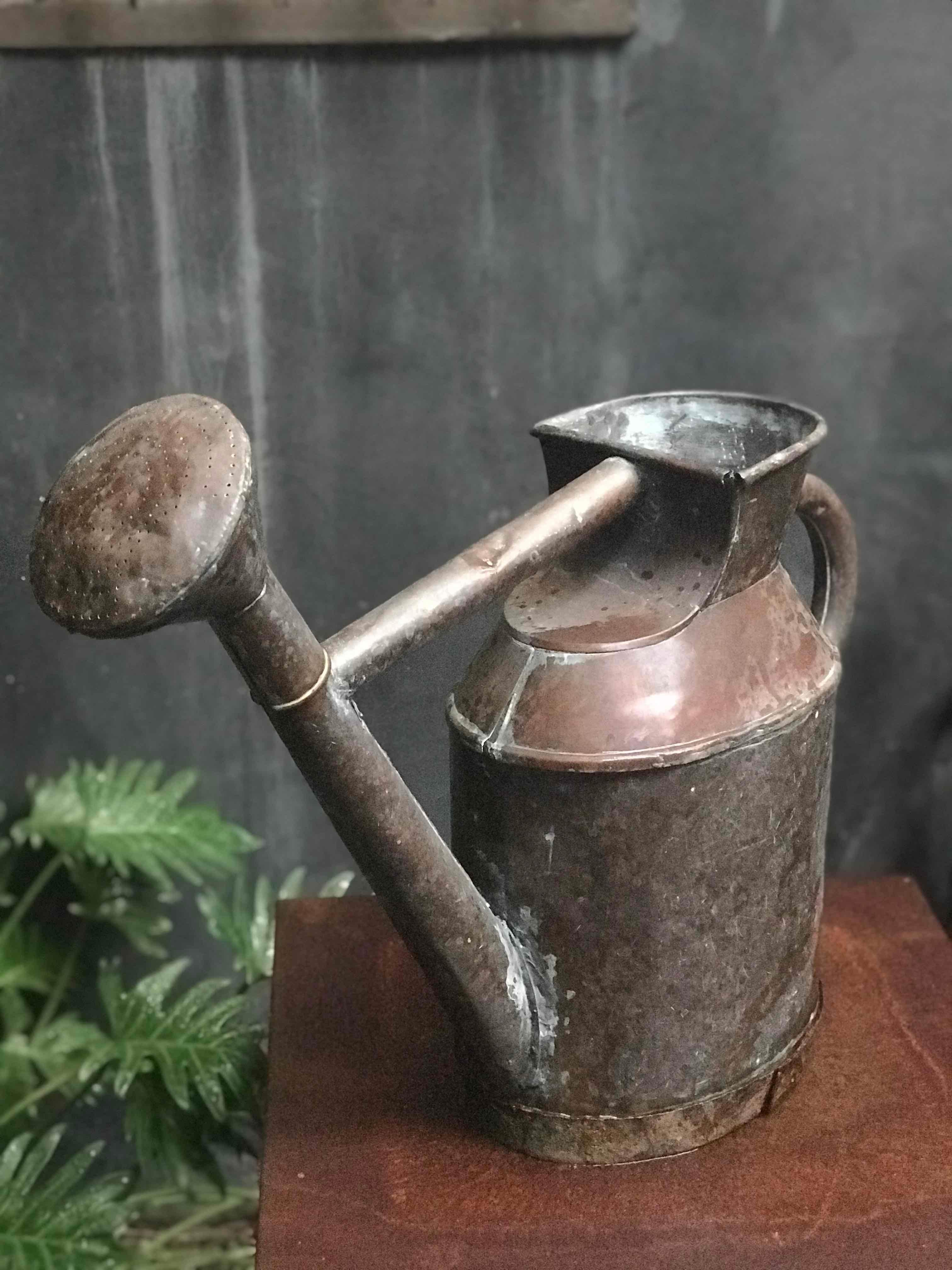 A copper watering can with an iron band at base, from England c. 1850. 