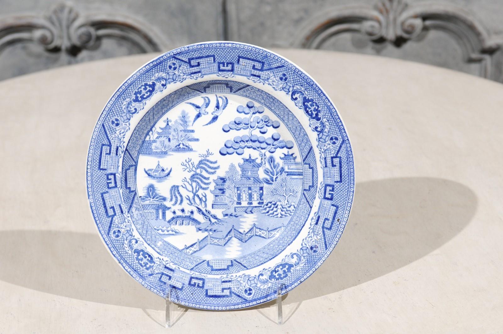 An English Wedgwood & Co. blue and white stoneware plate from the late 19th century, with willow pattern. Born in the Staffordshire County during the later years of the 19th century, this Wedgwood & Co. stoneware plate features an exquisite