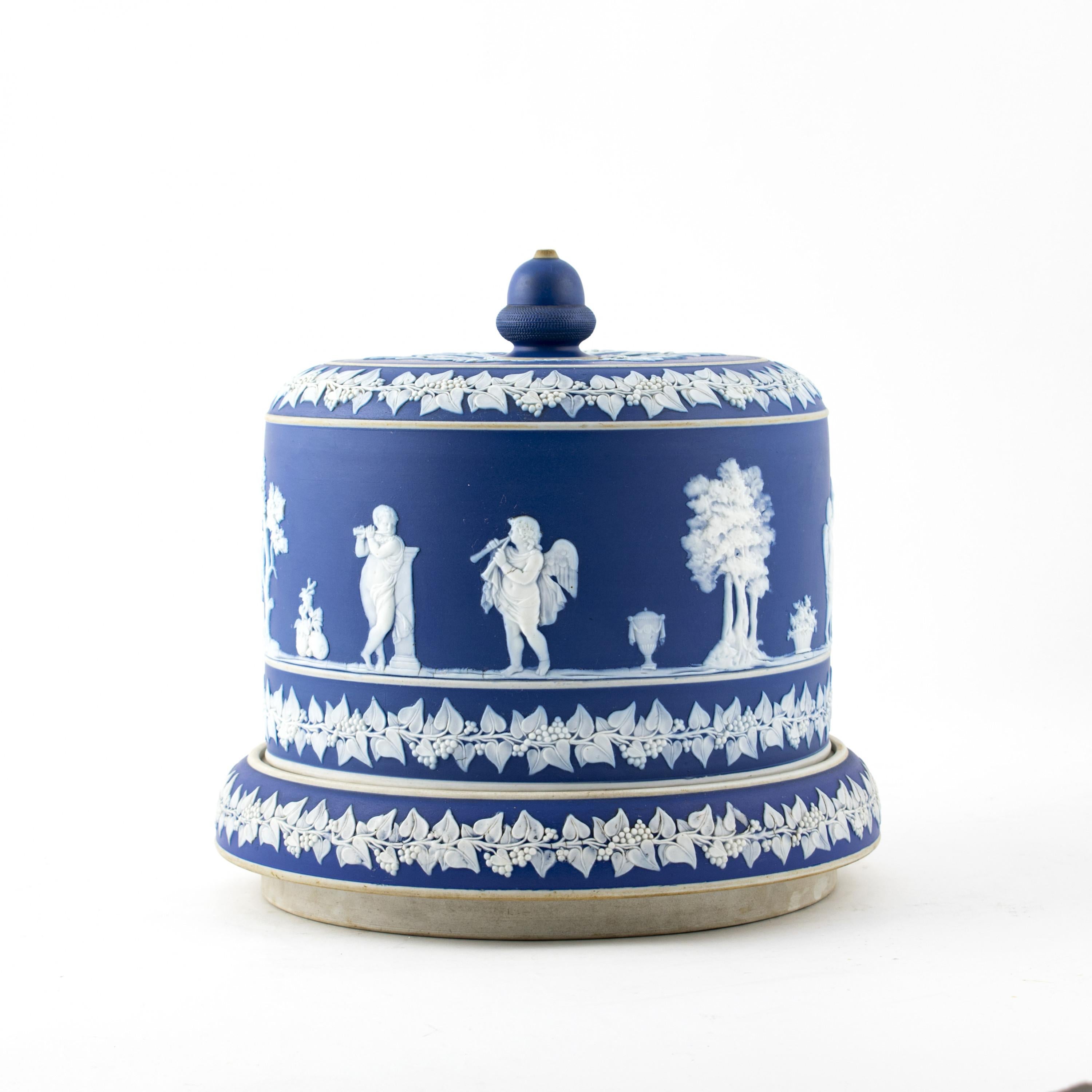 Large English Wedgwood Jasperware cheese dome.
Jasperware is usually described as stoneware, with an unglazed matte “biscuit” finish.
Beautiful overall raised neoclassical relief decorations of trees and angles.
Vine leaves and grapes bordering
