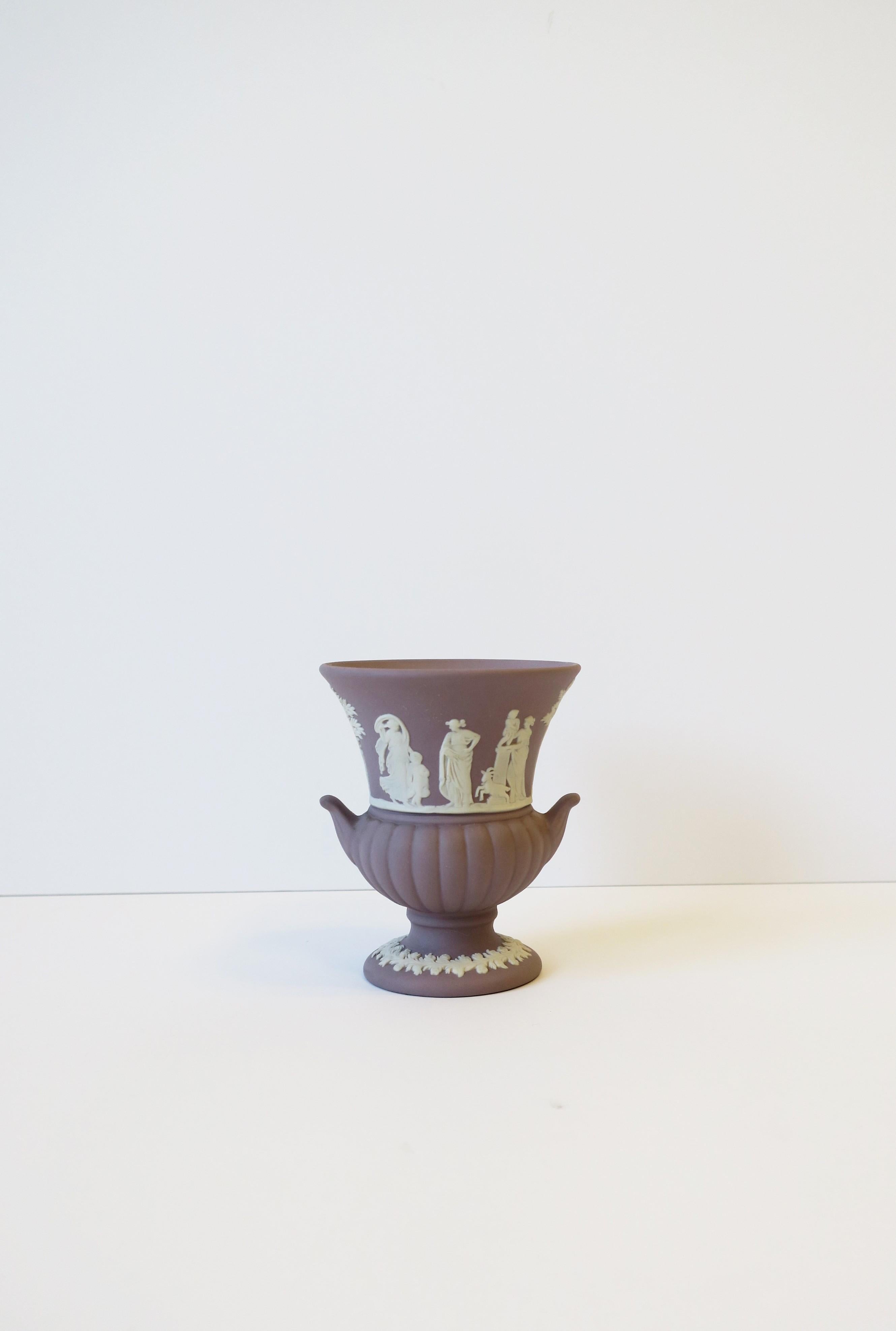 A beautiful, small, English Wedgwood Jasperware urn vase in the neoclassical design style, circa 20th century, England. Piece is a matte stoneware in a light lavender purple with a white neoclassical raised relief around center, a leaf design at