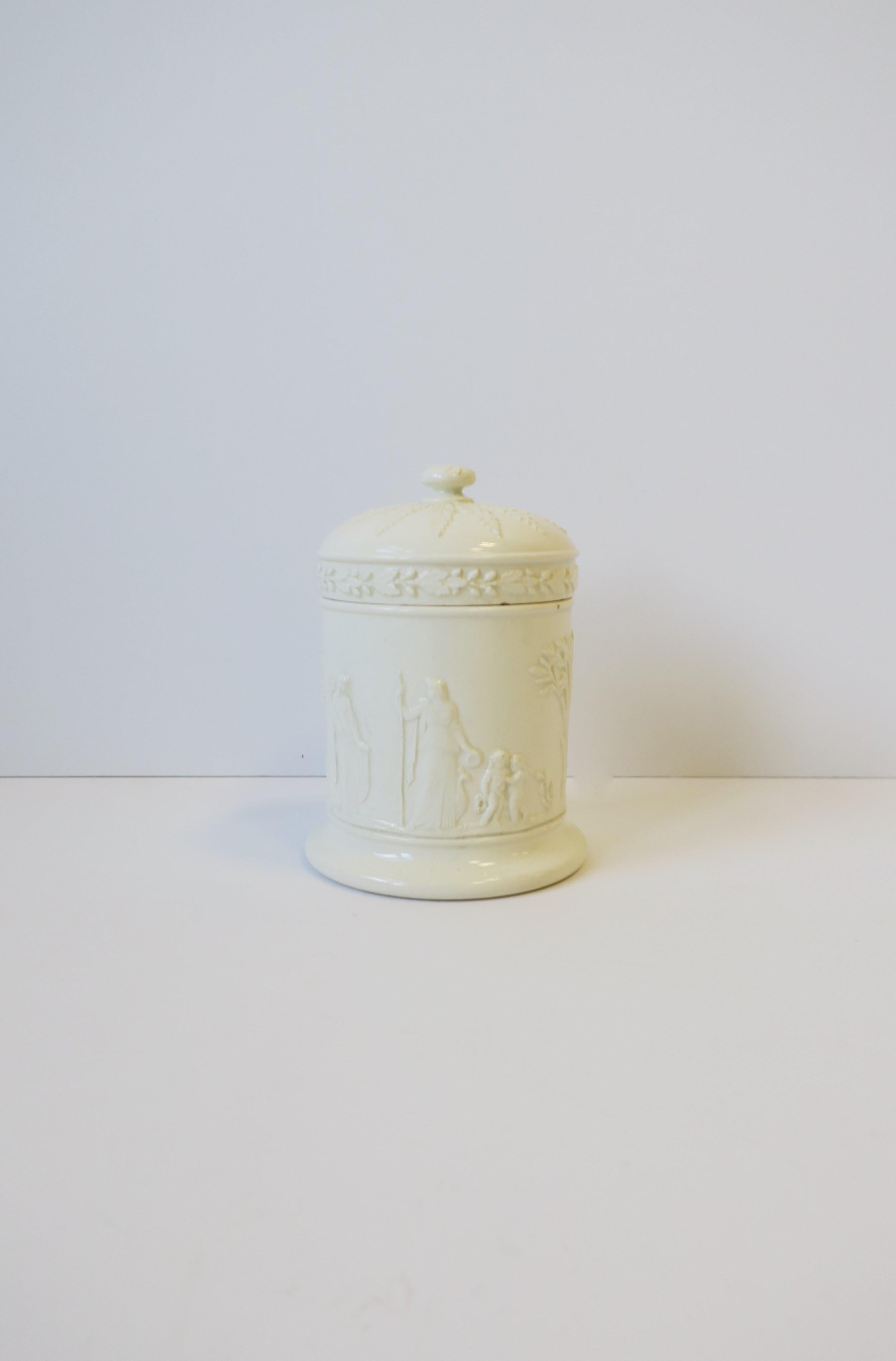 A beautiful off-white cream ceramic box jar with lid by Wedgwood, in the Neoclassical style, circa mid-20th century, England. With marker's mark on bottom as shown in image #12. Great as a standalone piece or to hold small items on a vanity,