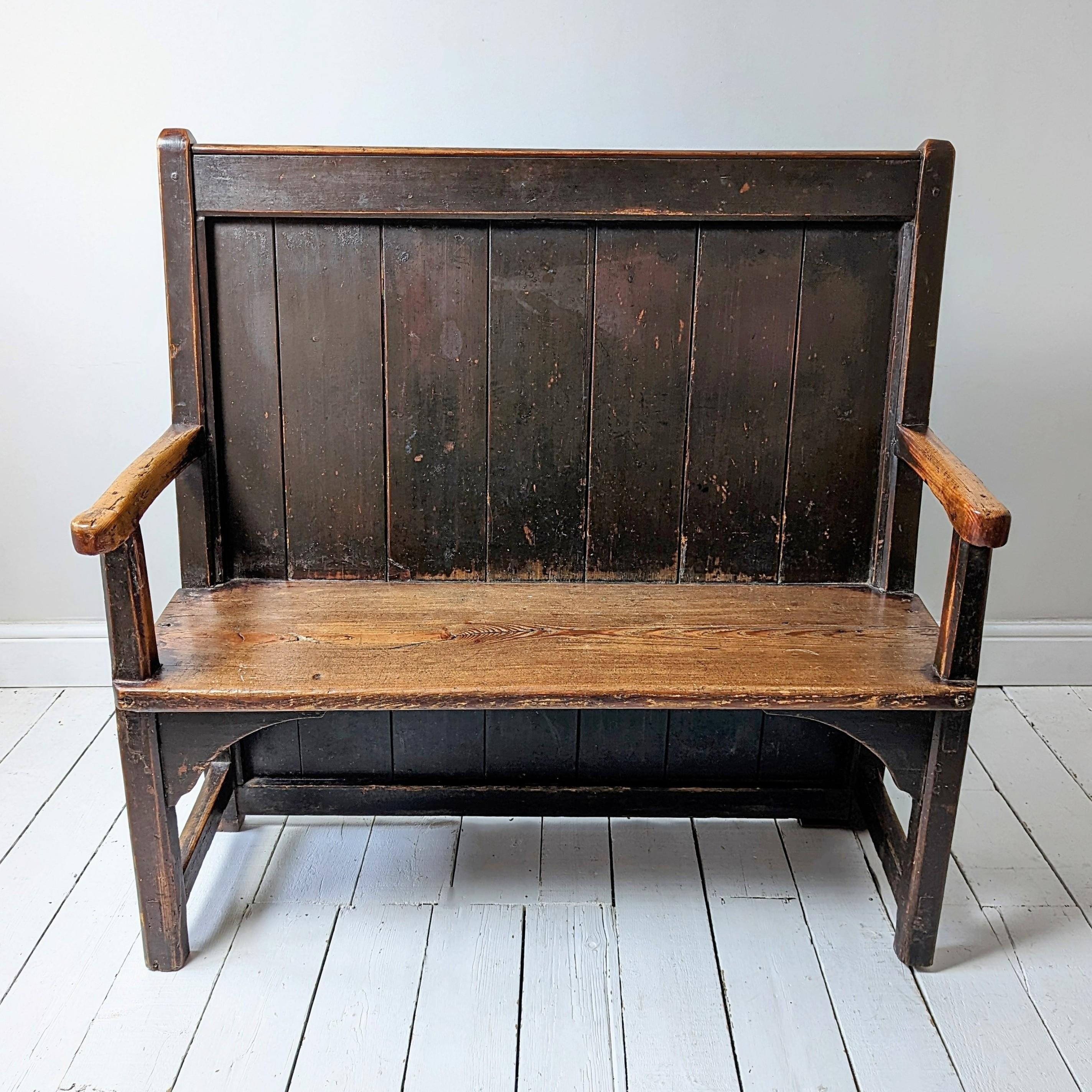 A West Country vernacular settle in oak and pine.

Of pegged construction with a raked back, scrolled arms, plank seat and legs with cuspate spandrels. 

A wonderful piece of country furniture of desirable small proportions.

In original