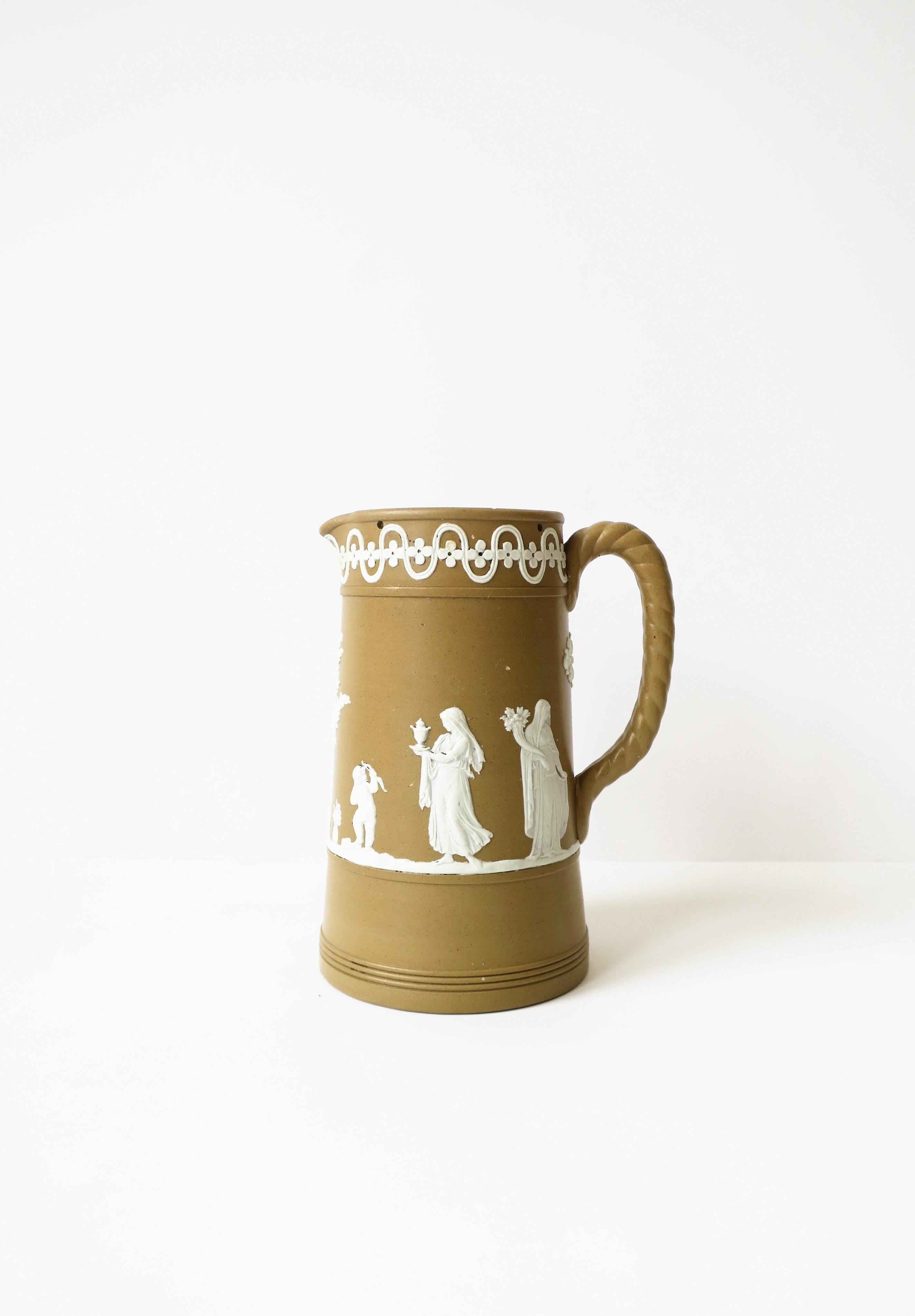 A beautiful 19th century English Dudson pottery Neoclassical white and brown Jasperware matte stoneware pottery pitcher, England. Piece is a mocha brown or light brown matte stoneware with a white neoclassical raised relief scene. Maker's marks on