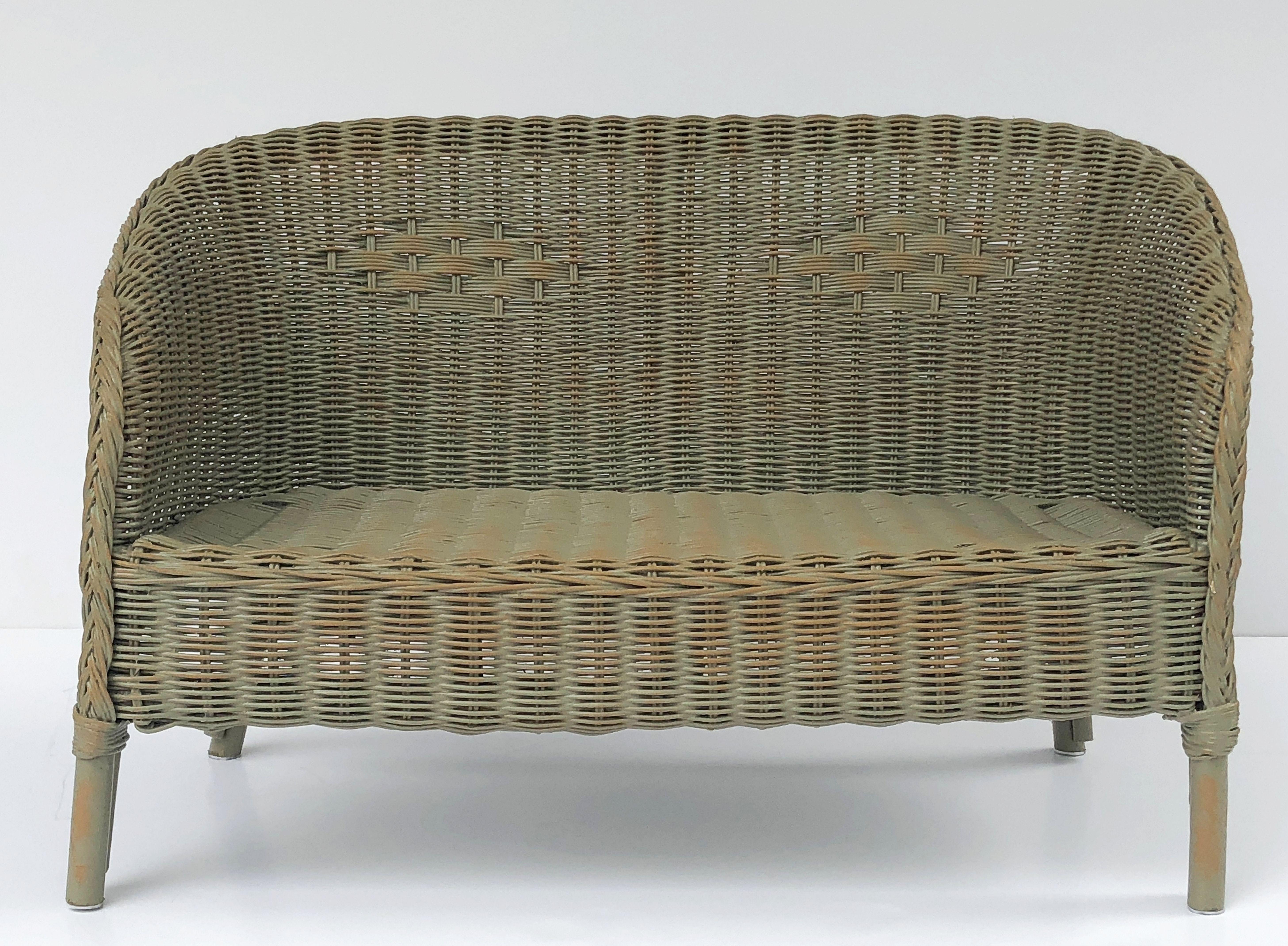A fine Lloyd Loom child's settee or seating bench sofa, synonymous with classic English style, featuring a settee of woven wicker and wire over a wood frame stretcher.

Perfect for an indoor or outdoor garden, garden room, or conservatory, this