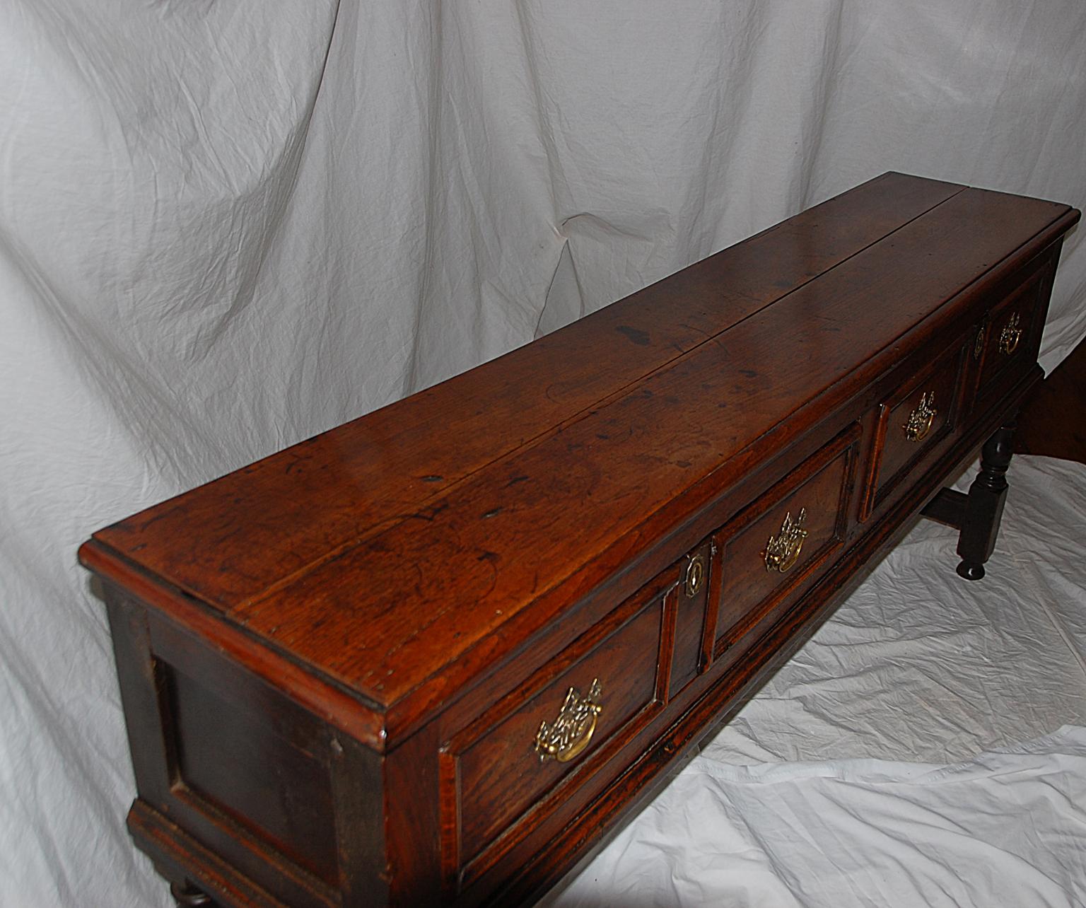 English William and Mary period oak low dresser with molded drawer fronts, top and edge skirting. The boldly turned front and back legs are connected by a short stretcher, the sides are paneled. This 73 1/2 inch handsome 17th century dresser has had