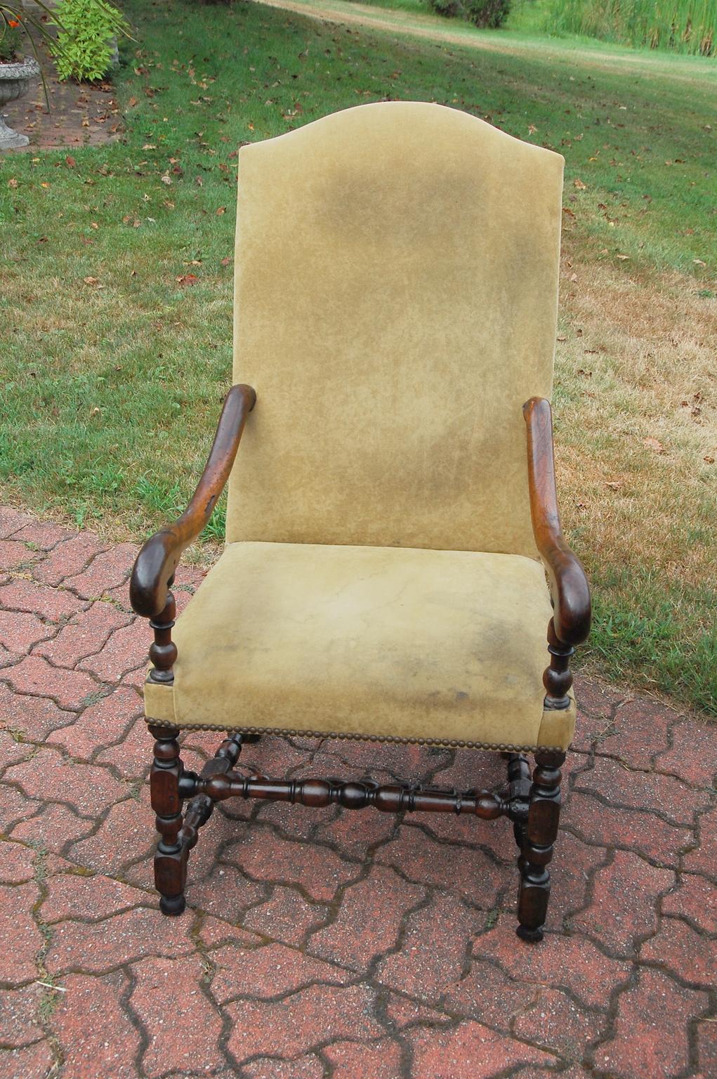 English William and Mary period walnut lounging chair. This handsome tall backed chair has carved scroll arms, beautifully turned legs, front stretcher and 