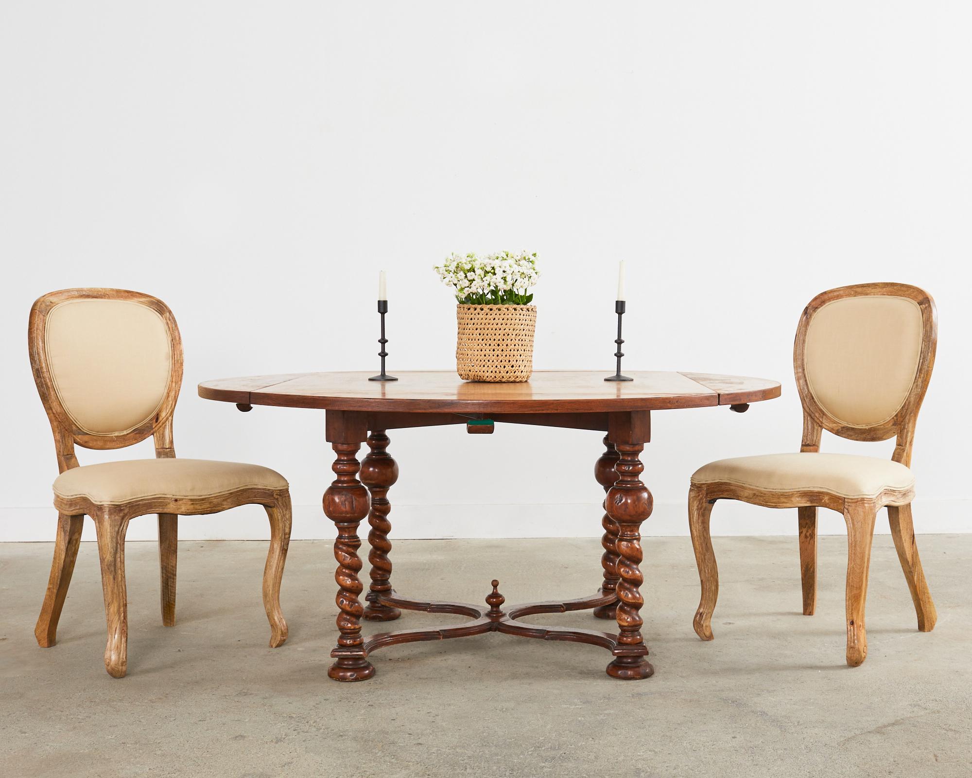 Magnificent country English dining table or center table featuring large barley twist legs. The round table has four drop-leaf sides converting the table from a 64 inch diameter circle to a 45.5 inch wide square table. The 1 inch thick top is