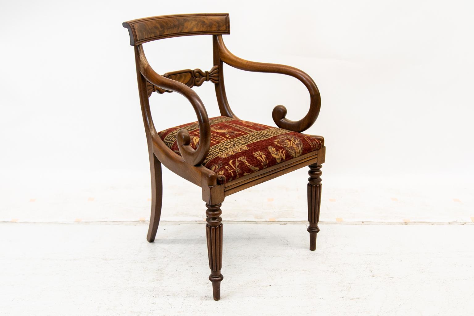English William IV armchair has a carved crest rail framing a flame grained mahogany panel. The front legs are fluted, and the arms have a scrolled shaping.
  