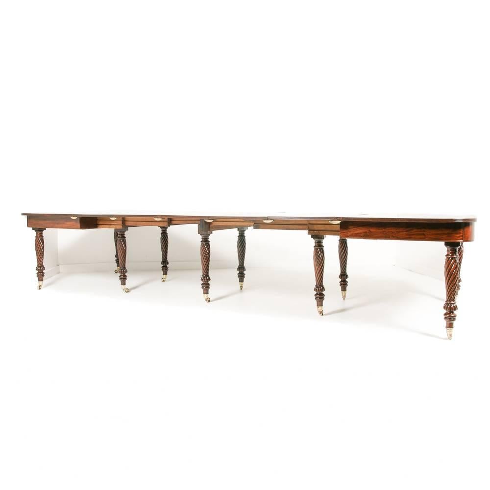 A grandly-proportioned and elegant English banded mahogany extending dining table.

Comprised of two ‘D’ consoles which bolt together and telescope out, this banquet-size dining table has seven solid mahogany leaves banded in satinwood, and is