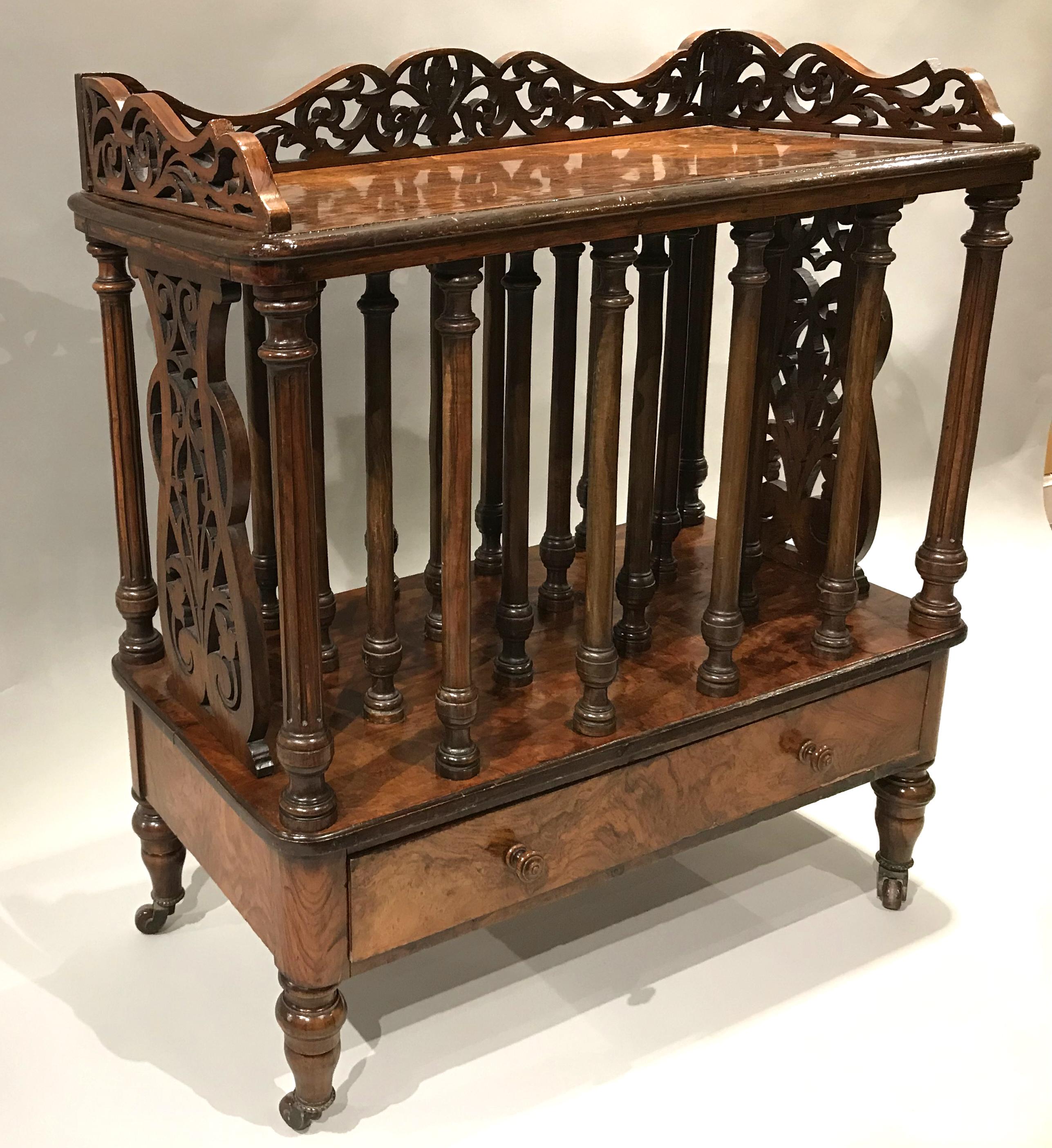 A fine English William IV burled walnut Canterbury with single lower drawer, splendid pierce carved lyre ends and gallery, turned central column dividers, all supported on turned legs with porcelain casters. Dates to the late 18th or early 19th