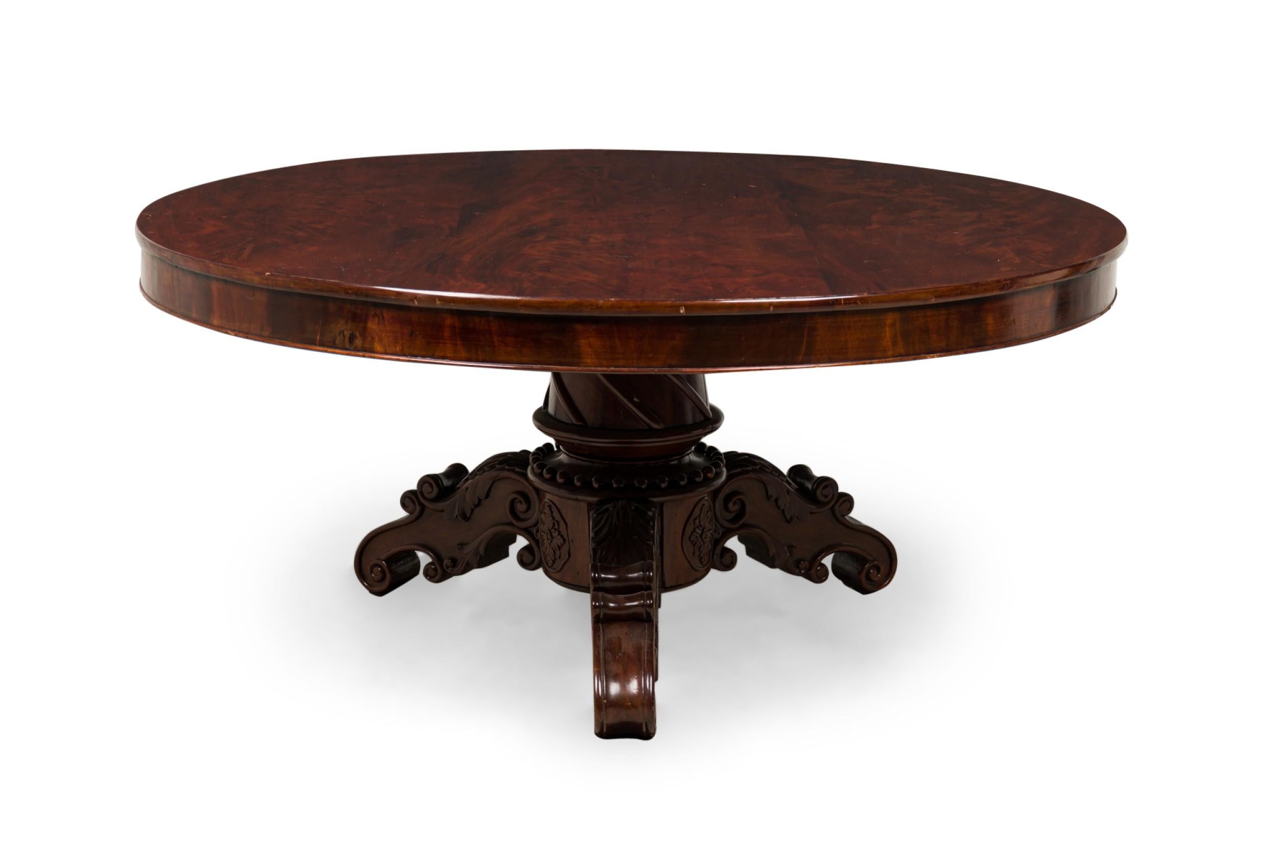 English William IV (19th Century) mahogany veneer dining / center table with a circular top resting on a turned pedestal base with three scroll carved legs.

Some top surface wear, losses on trim.