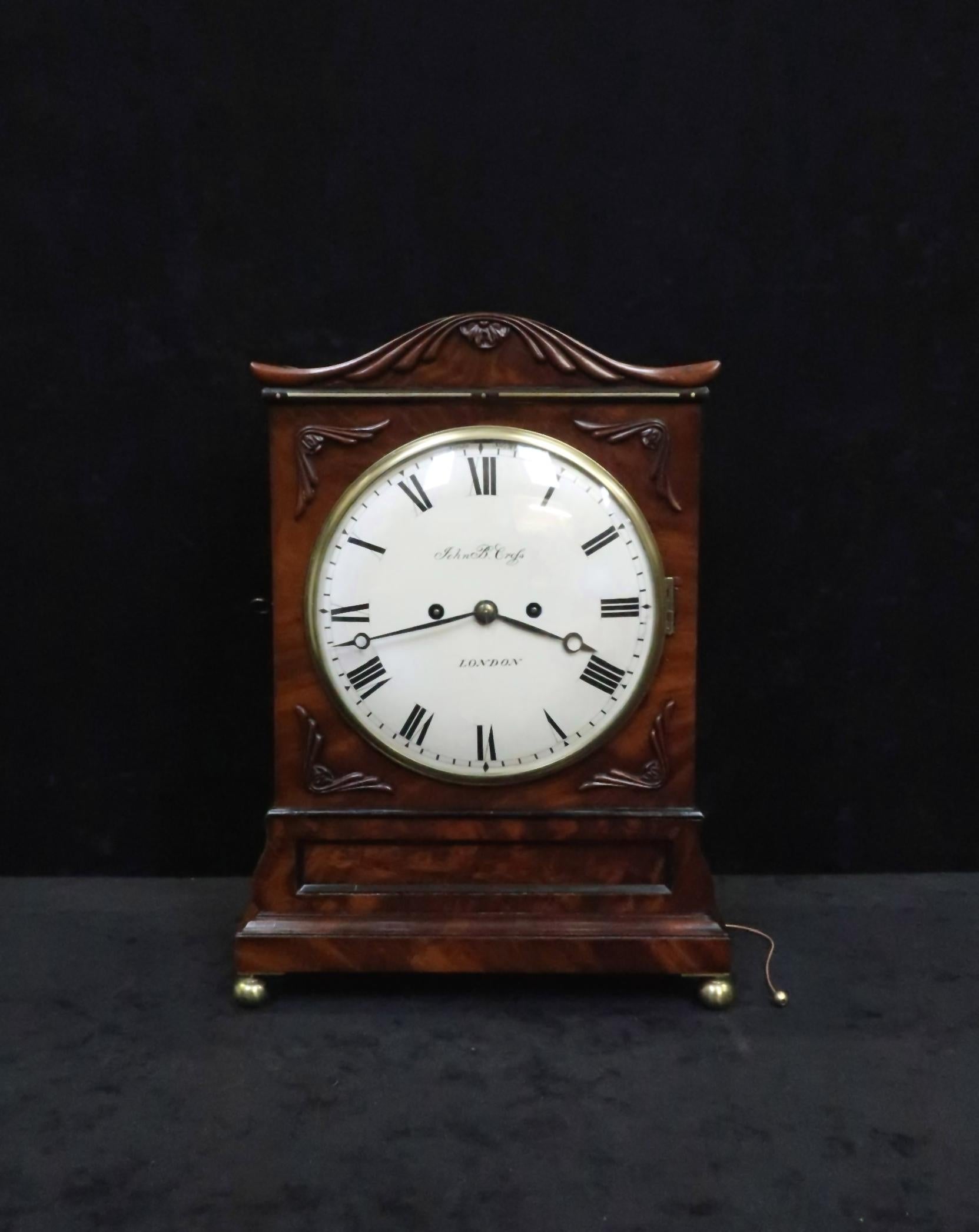 A excellent quality English William IV figured mahogany bracket clock with applied honeysuckle carving, shaped top, ebonized moulds, Gothic style brass sound frets to the side stood on brass ball feet.

The clock has an eight inch painted dish
