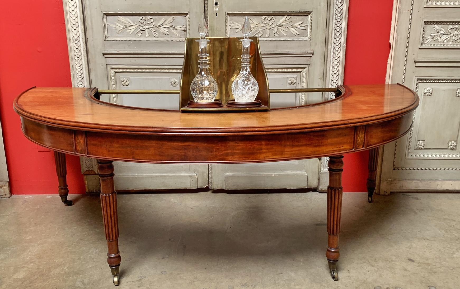 A semi circular English William IV walnut and mahogany hunt table with a removable brass decanter holder that swivals from end to end. This table was used for serving drinks to hunters like a self service bar. The brass pieces are easily removed