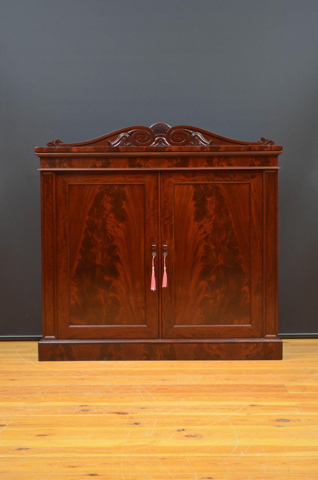 Sn5572 Fine quality William IV two door side cabinet in mahogany, having finely carved upstand to the back and figured mahogany top above shallow frieze and a pair of panelled, flamed mahogany door fitted with turned knobs, working locks and keys,