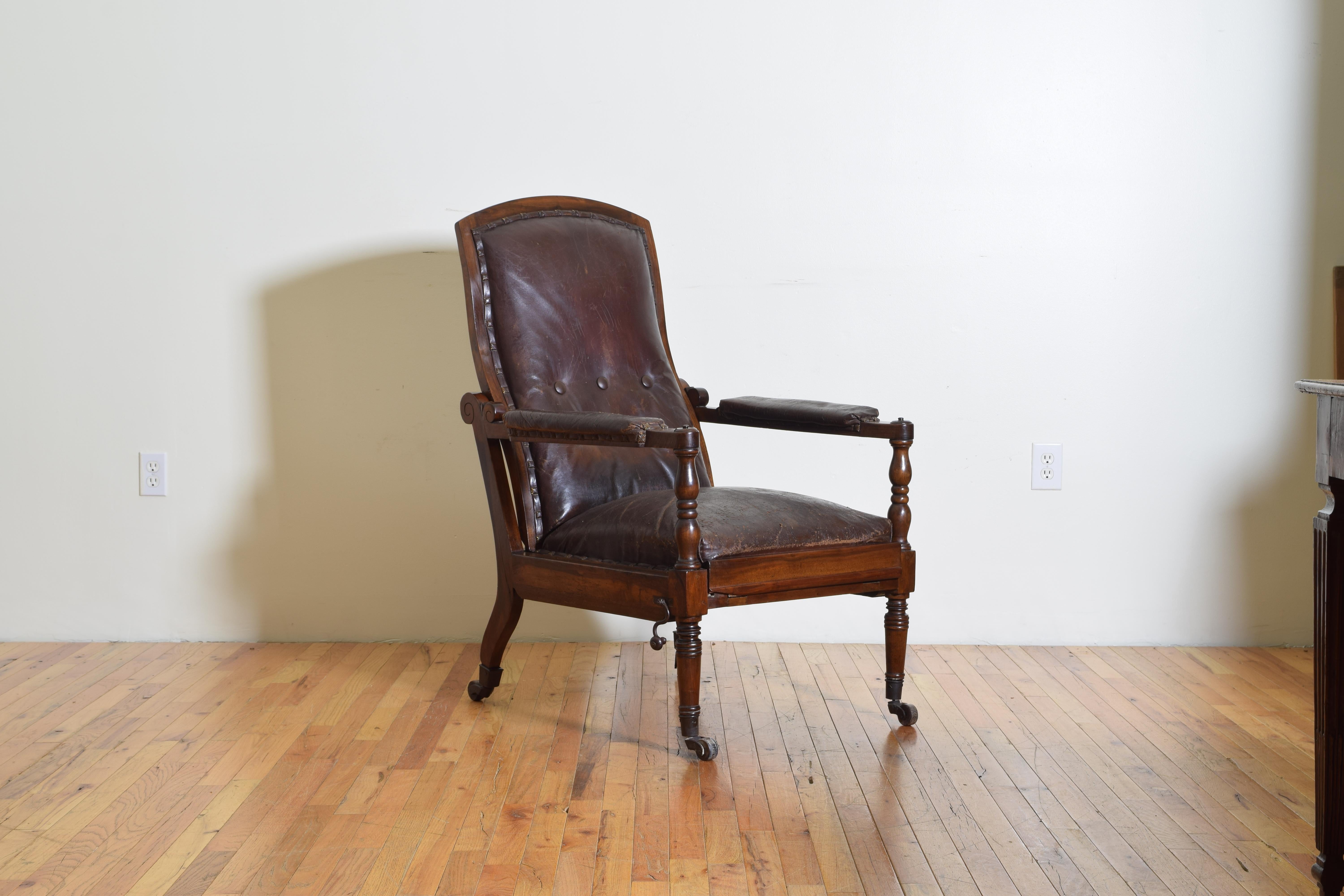 The chair having an arched backrest upholstered in button tufted brown leather, the armrests also with leather cushions and turned supports, the seat of tightly upholstered in leather, raised on splayed back and turned front legs, all atop brass and