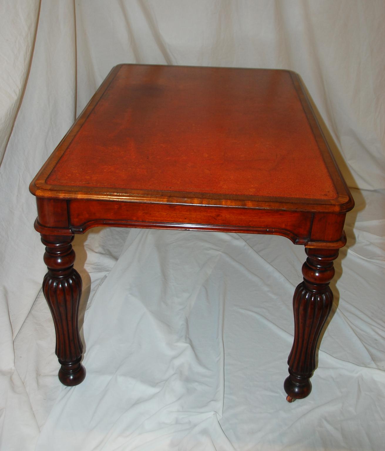 English William IV period mahogany writing table with inset gold tooled old leather writing surface, turned and reeded shaped legs, molded curved skirt to all sides. This medium sized writing table exudes the stylishness of William IV without being