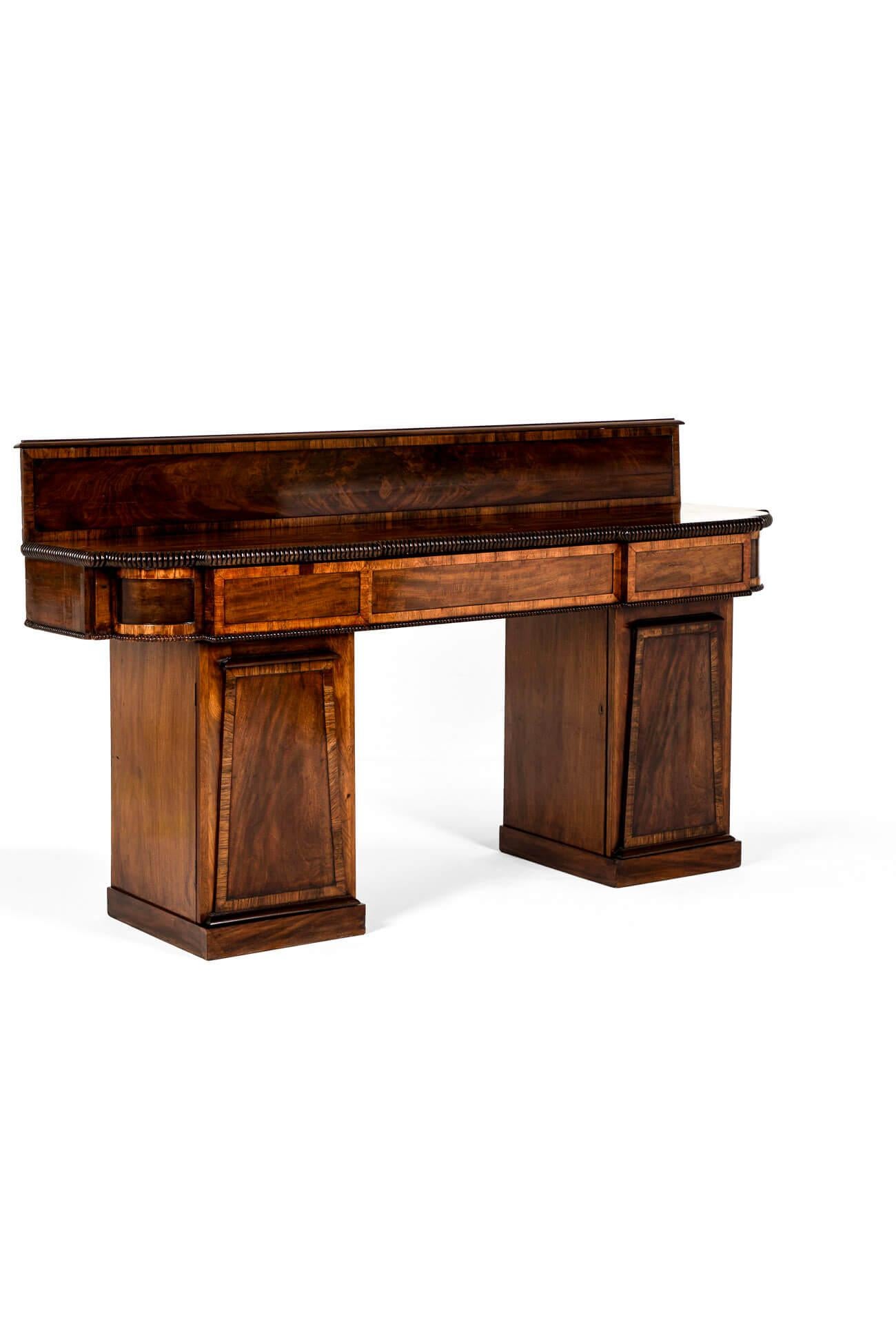 A beautiful William IV mahogany twin pedestal sideboard or serving table in exceptional condition.

The sideboard has an inverted break centre top with a half gallery and three frieze drawers with the fronts and sides crossbanded with