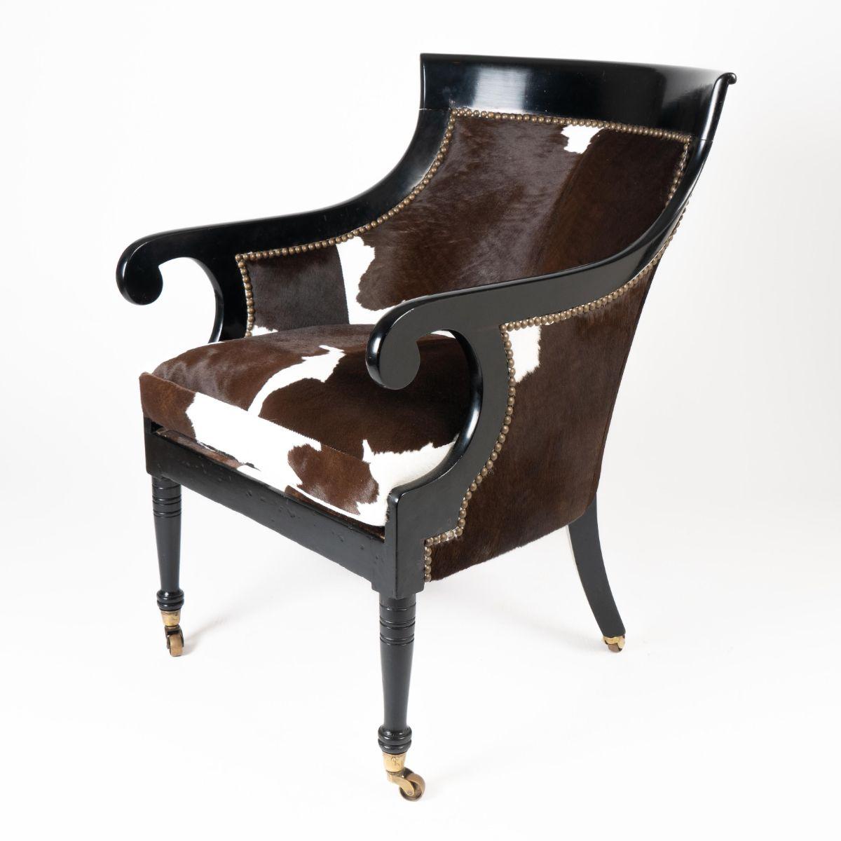 William IV painted mahogany framed gondola arm chair on cast brass castors. The frame is upholstered in chocolate brown and white calf skin hide on horse hair fill.

England, circa 1825.