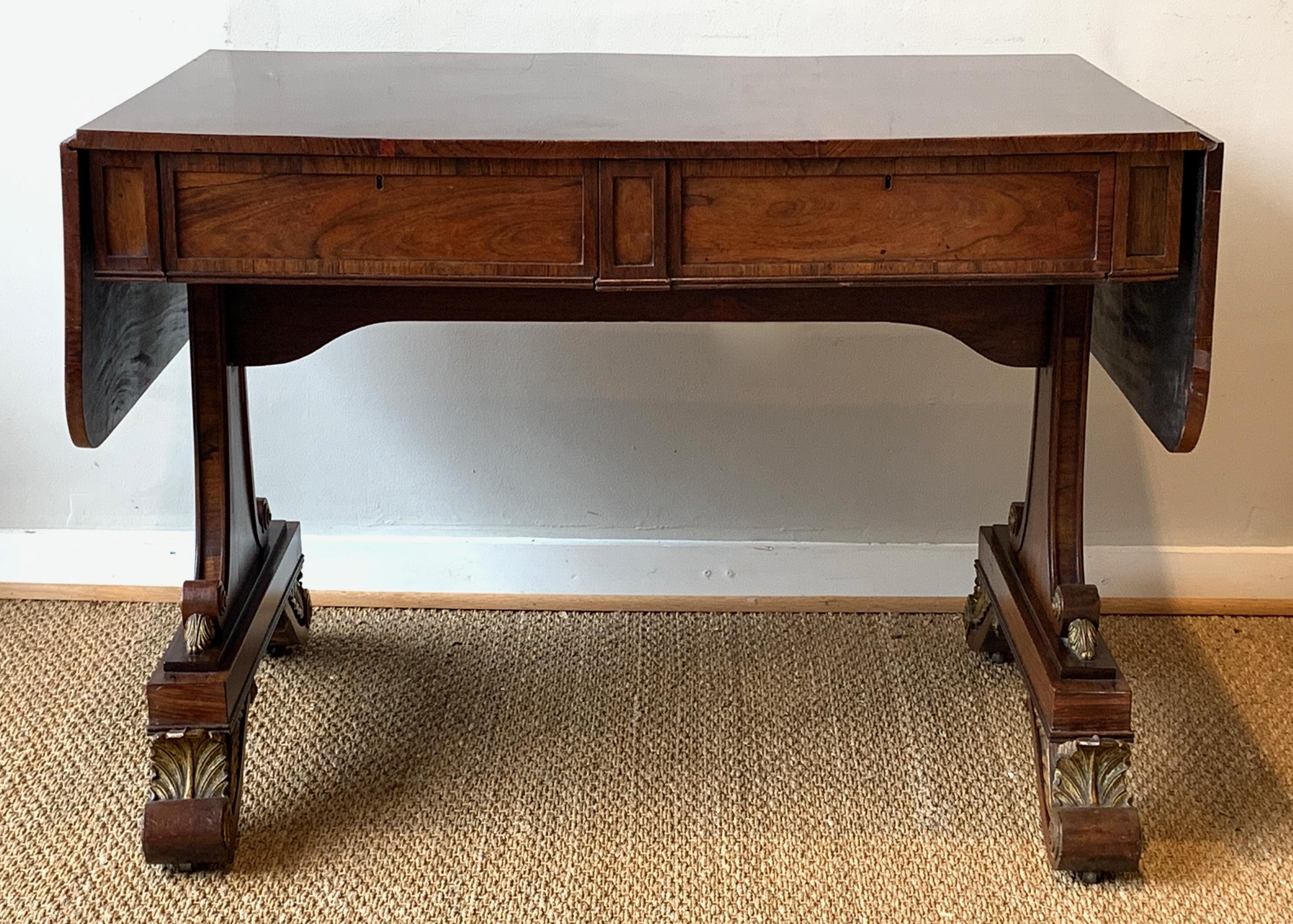 An exceptional early 19th century William IV sofa table attributed to Gillows. The beautifully figured, drop-leaf top above two concealed drawers and two dummy drawers resting on gently curving legs terminating in carved acanthus leaf and scrolled