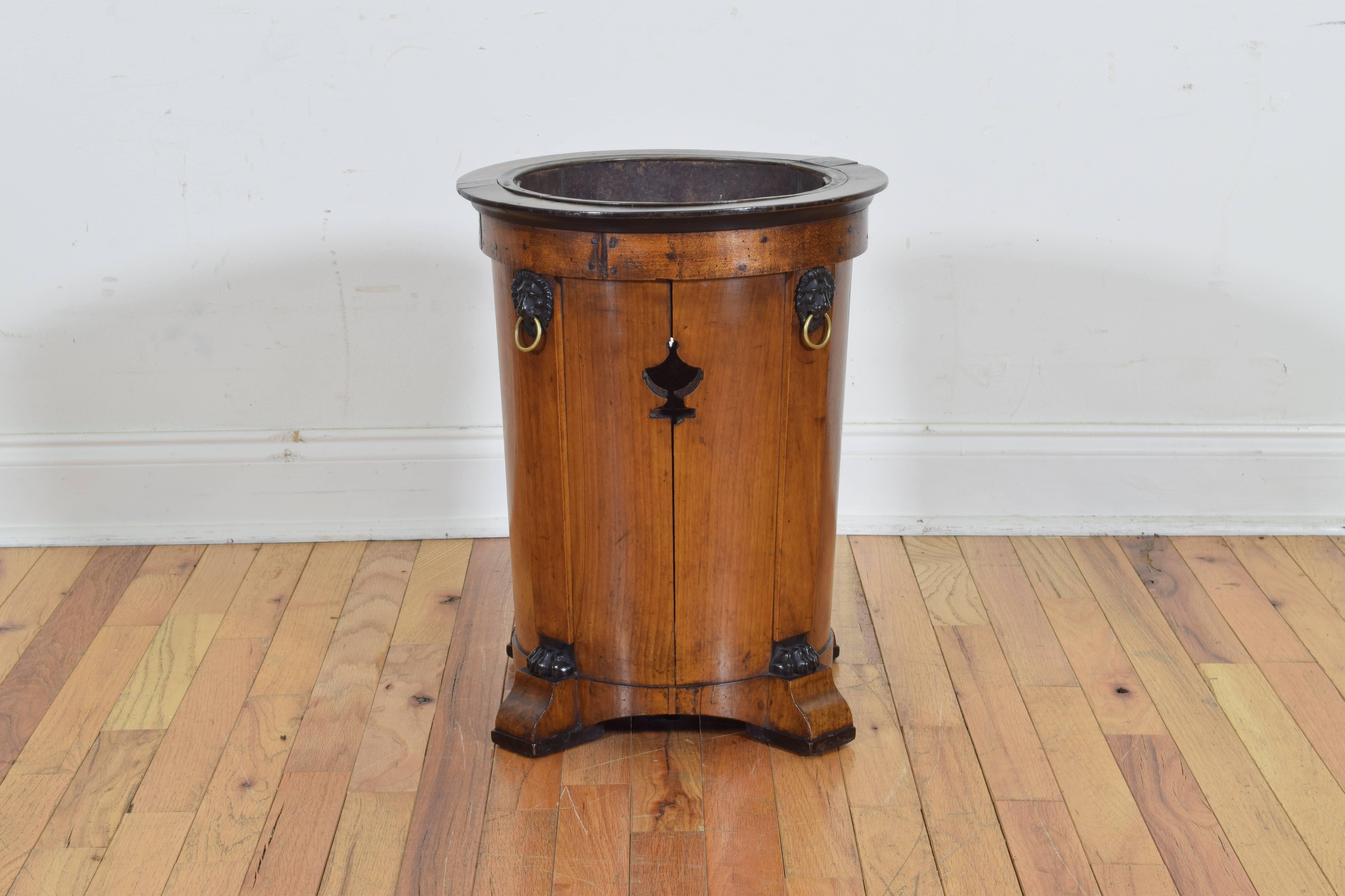 Complete with original tole liner, the openings in the wooden frame aligning with the liner in the shape of an urn, of tapering cylindrical form with raised pilasters topped by lion masks with brass rings, the lower part of the pilasters with paw
