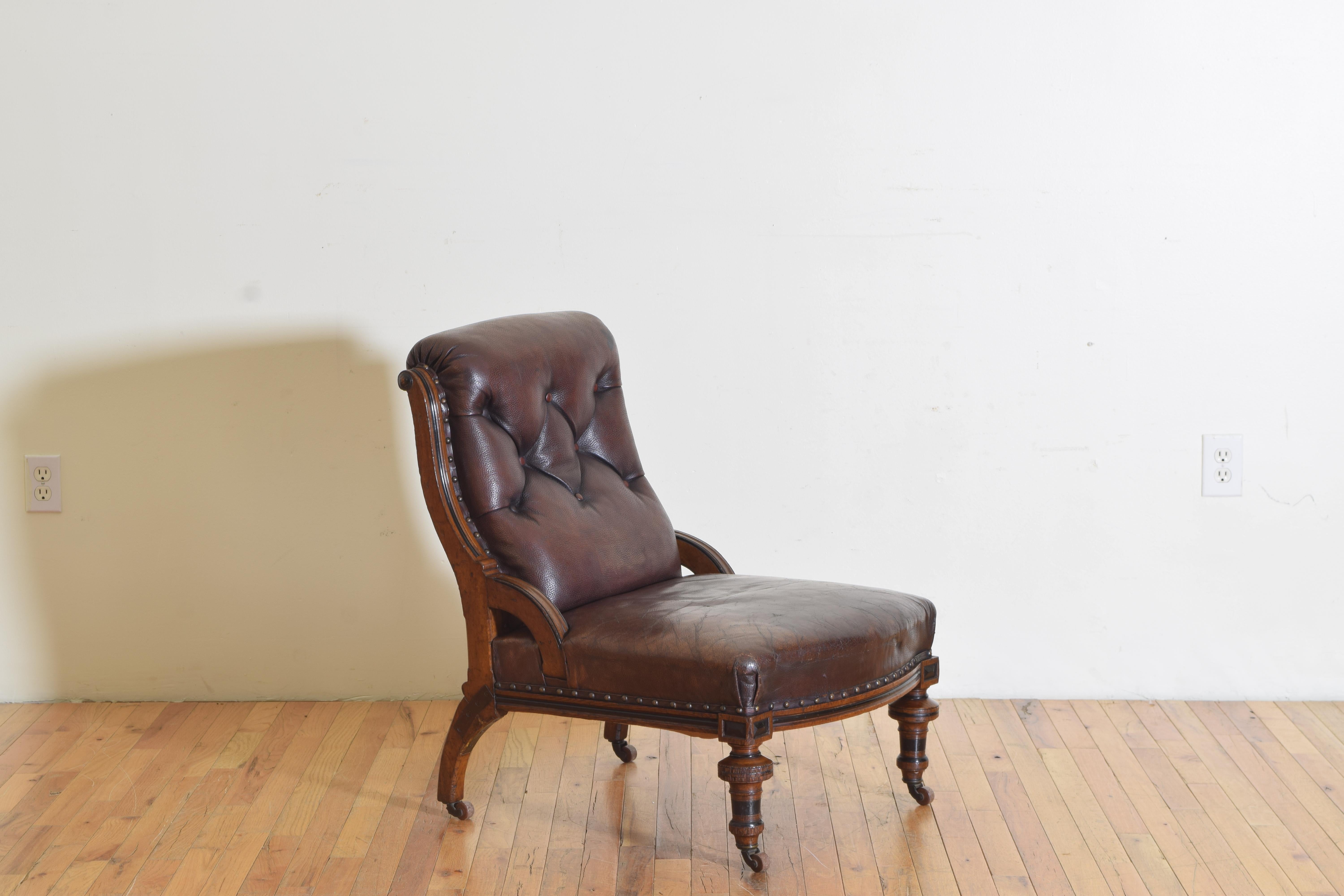 Having button tufted leather upholstery with brass nailhead trim, on block and turned legs and casters, with arched supports joining seat and back with iron bracing at rear splayed legs.
