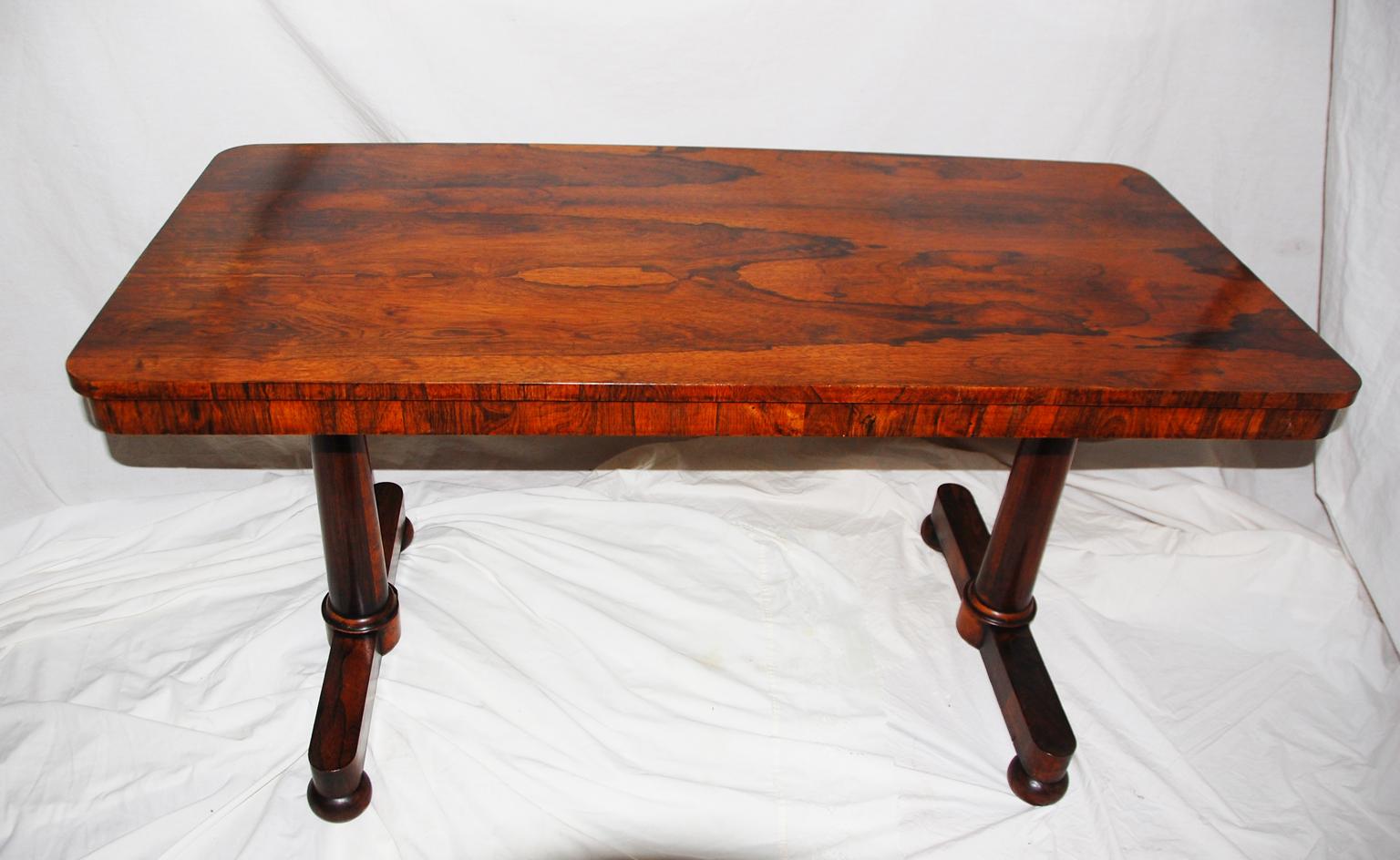 English William IV period rosewood library table with tapered pedestal ends and bun feet. The top edge is crossbanded in rosewood as is the skirting which supports the top. At 54 inches long and 25 1/2 inches deep it is easy to use in most rooms as