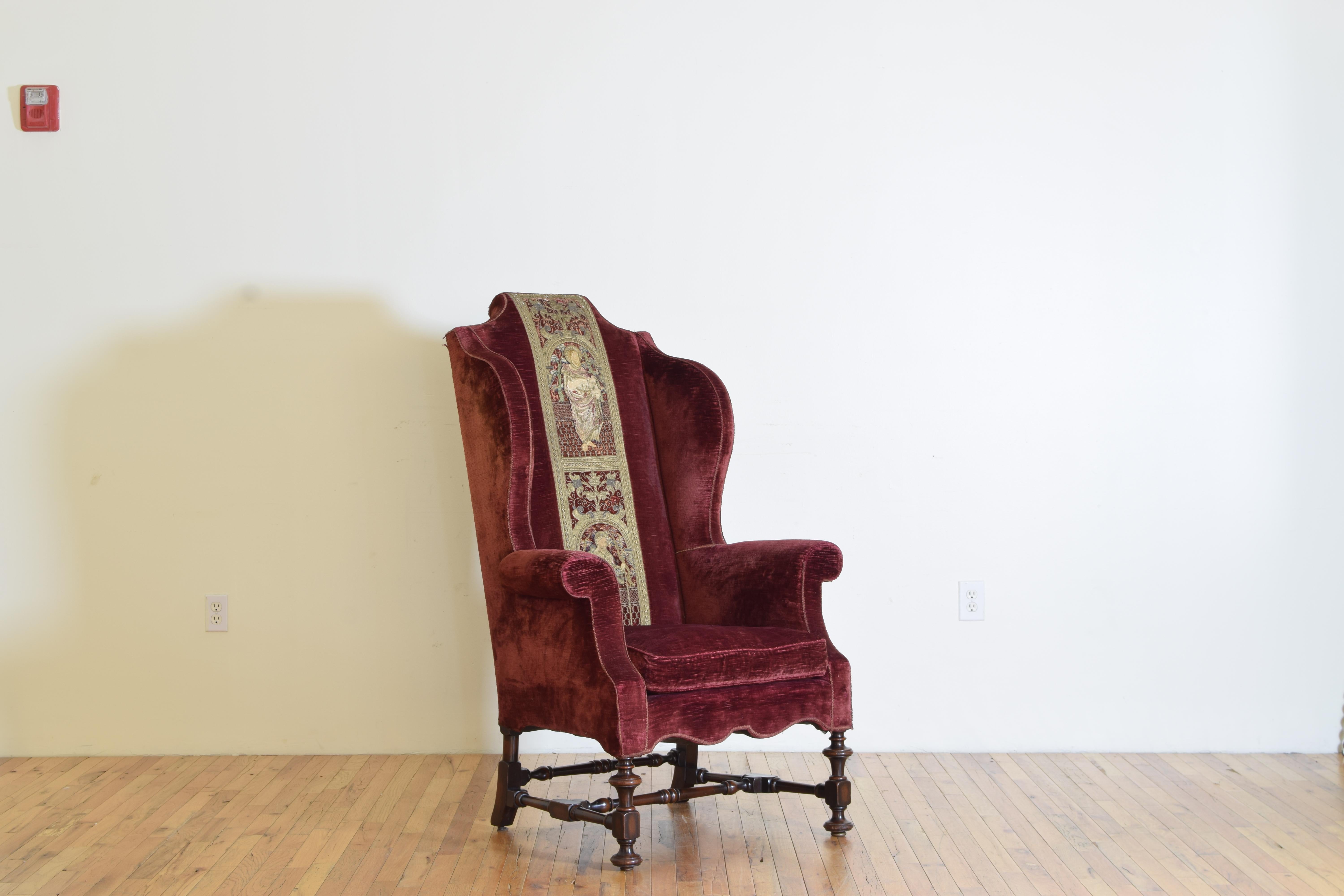 Of large proportion and very comfortable, retaining its original velvet upholstery this wingchair has a unique feature in that the decorative elements is woven from gold and silk threads and was likely originally from a vestment worn by clergy, the