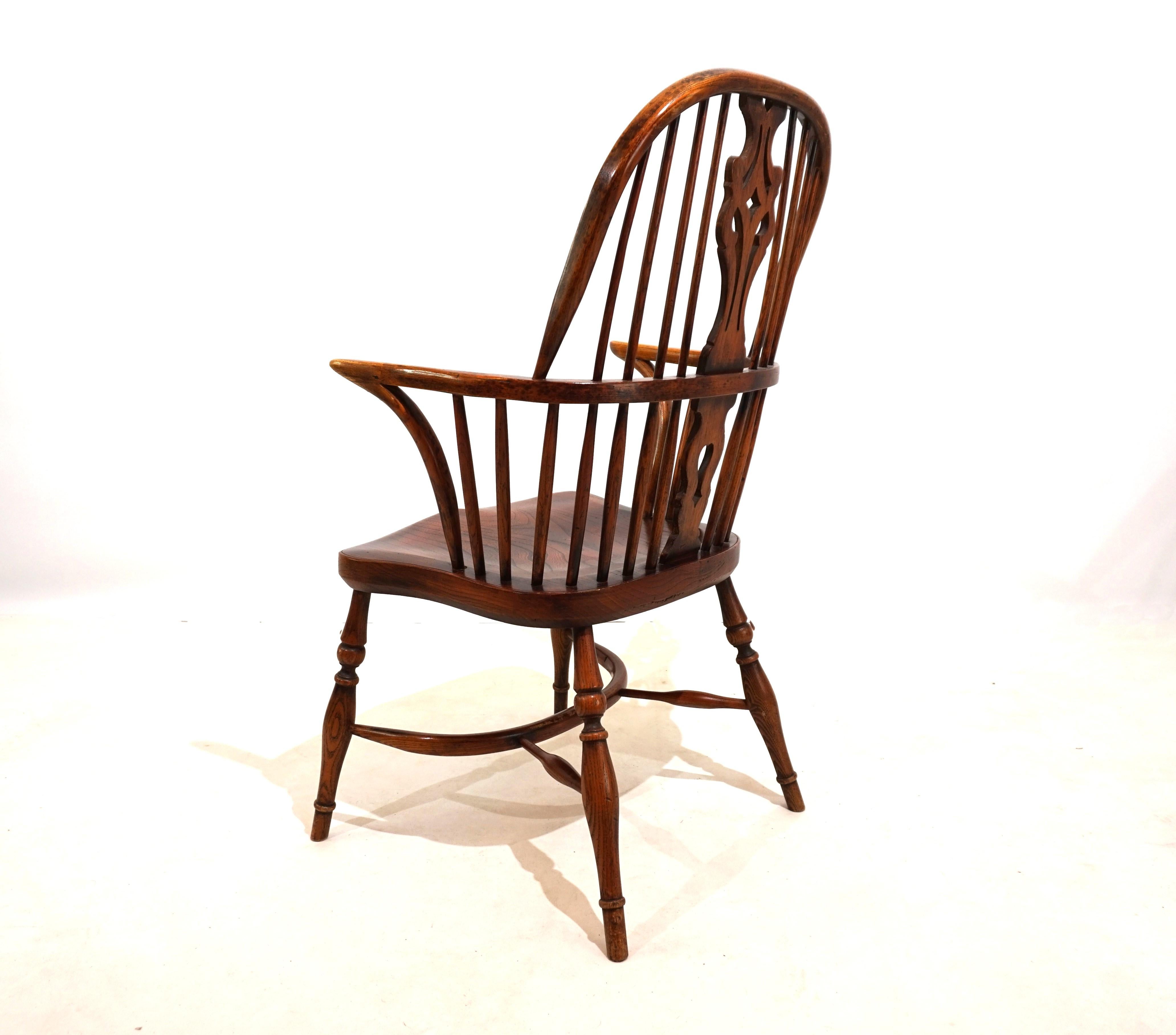 Cette chaise Windsor en version fauteuil avec dossier est en très bon état avec une fantastique patine d'âge. L'élément de conception du dossier et les entretoises simples et délicates confèrent à la chaise une apparence exclusive. Au fil des