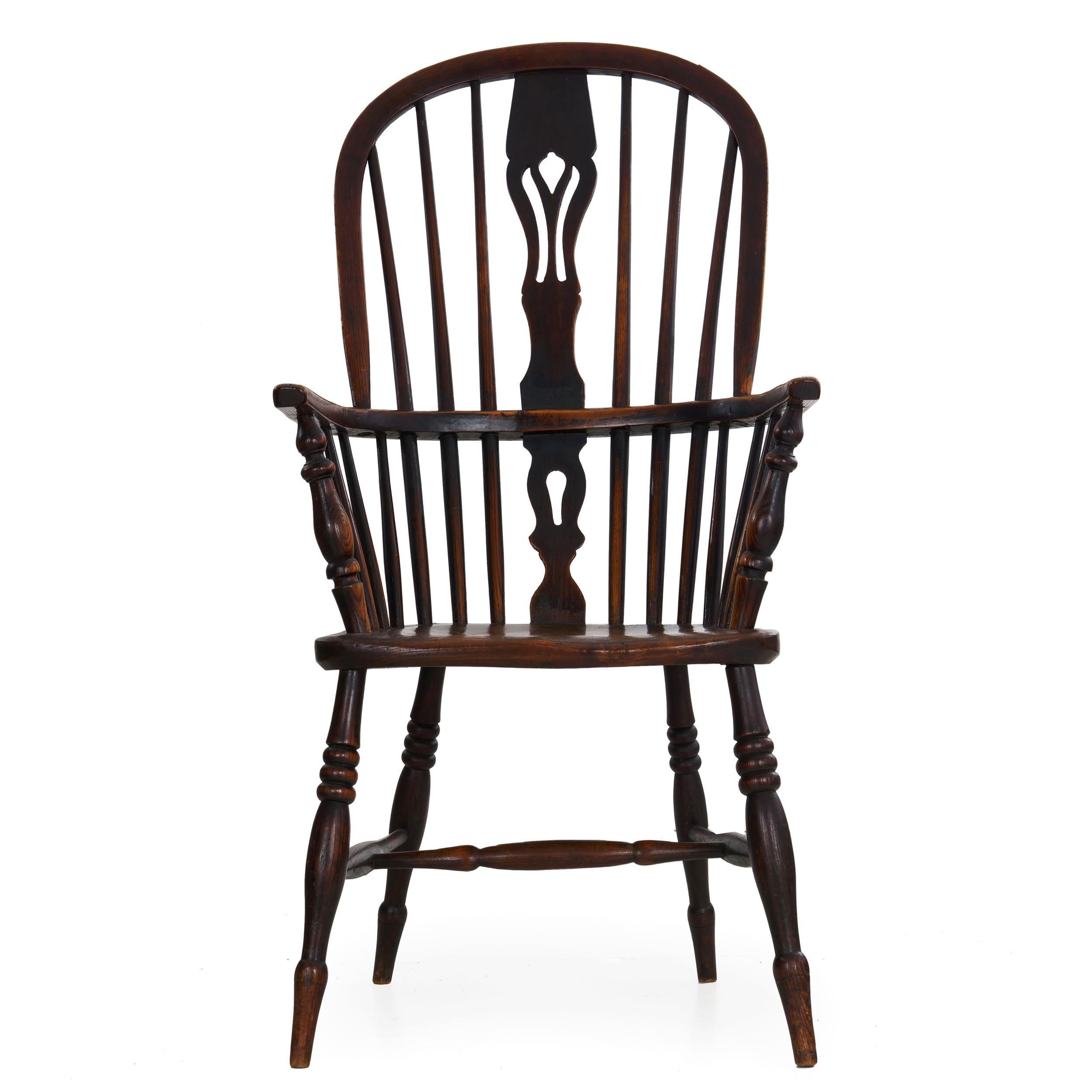 A fine English high-back Windsor armchair with a steam bent crest rail and arm rail of polished yew, through which are held six tapered spindles flanking a pierced splat, the arms raised over turned supports set within a shaped seat of elm, all