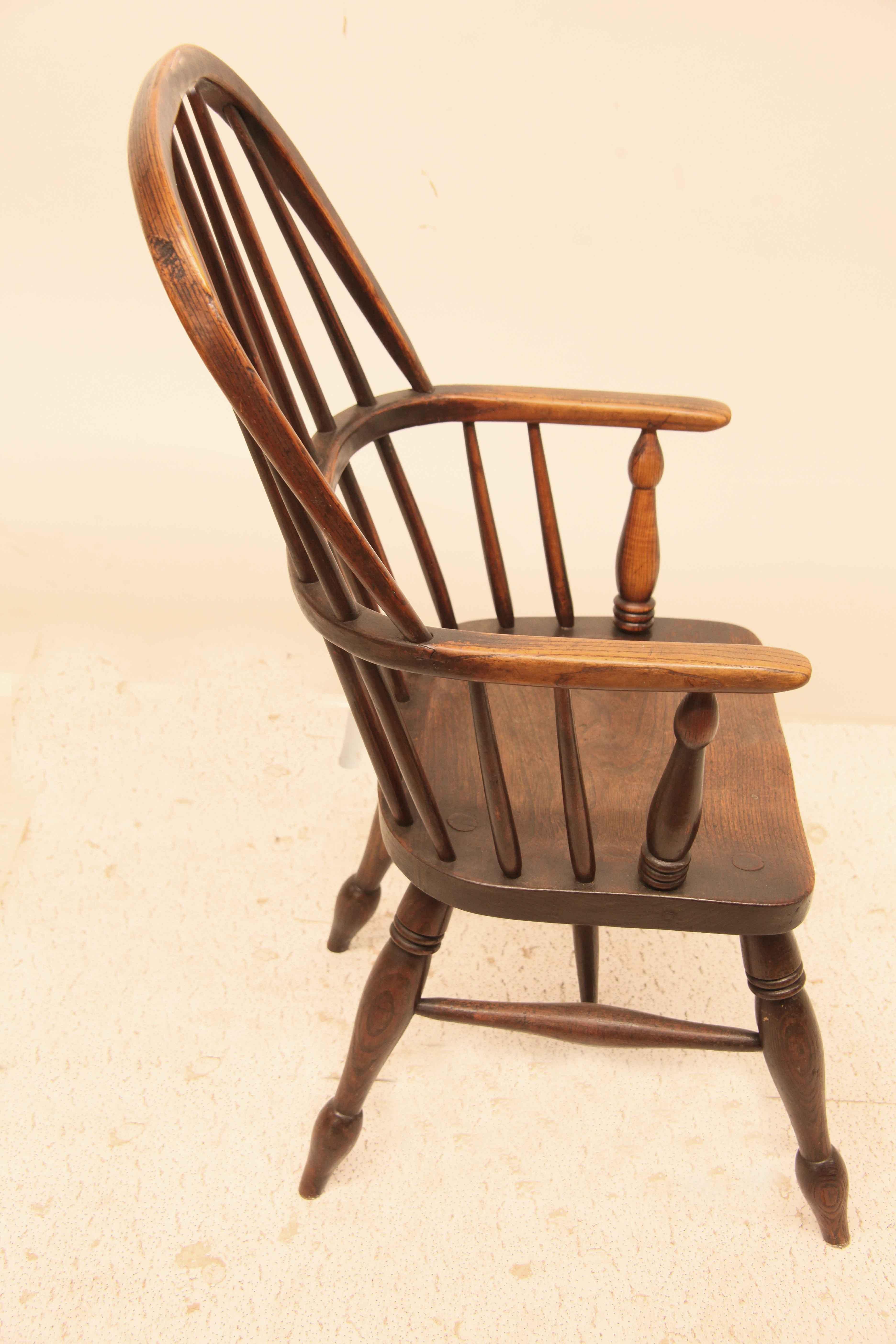 Chaise anglaise Windsor pour jeunes,  Cette chaise à dossier en fuseau est entièrement fabriquée en orme anglais.  Les accoudoirs droits présentent une belle usure naturelle, de même que l'assise.  Les pieds tournés sont munis de brancards qui