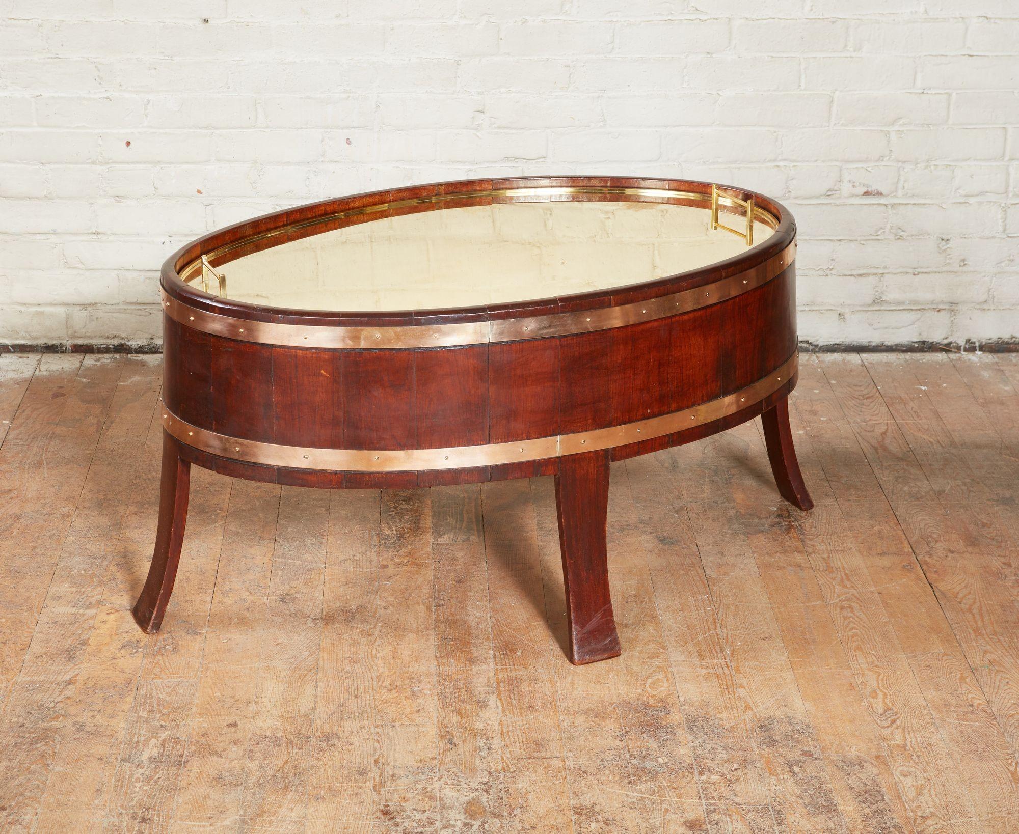Good early 20th century teak wine cooler/coffee table of oval form, with barrel stave construction and heavy gauge brass banding, having splayed legs and now with fine quality custom brass lid, the whole with good color and patination.