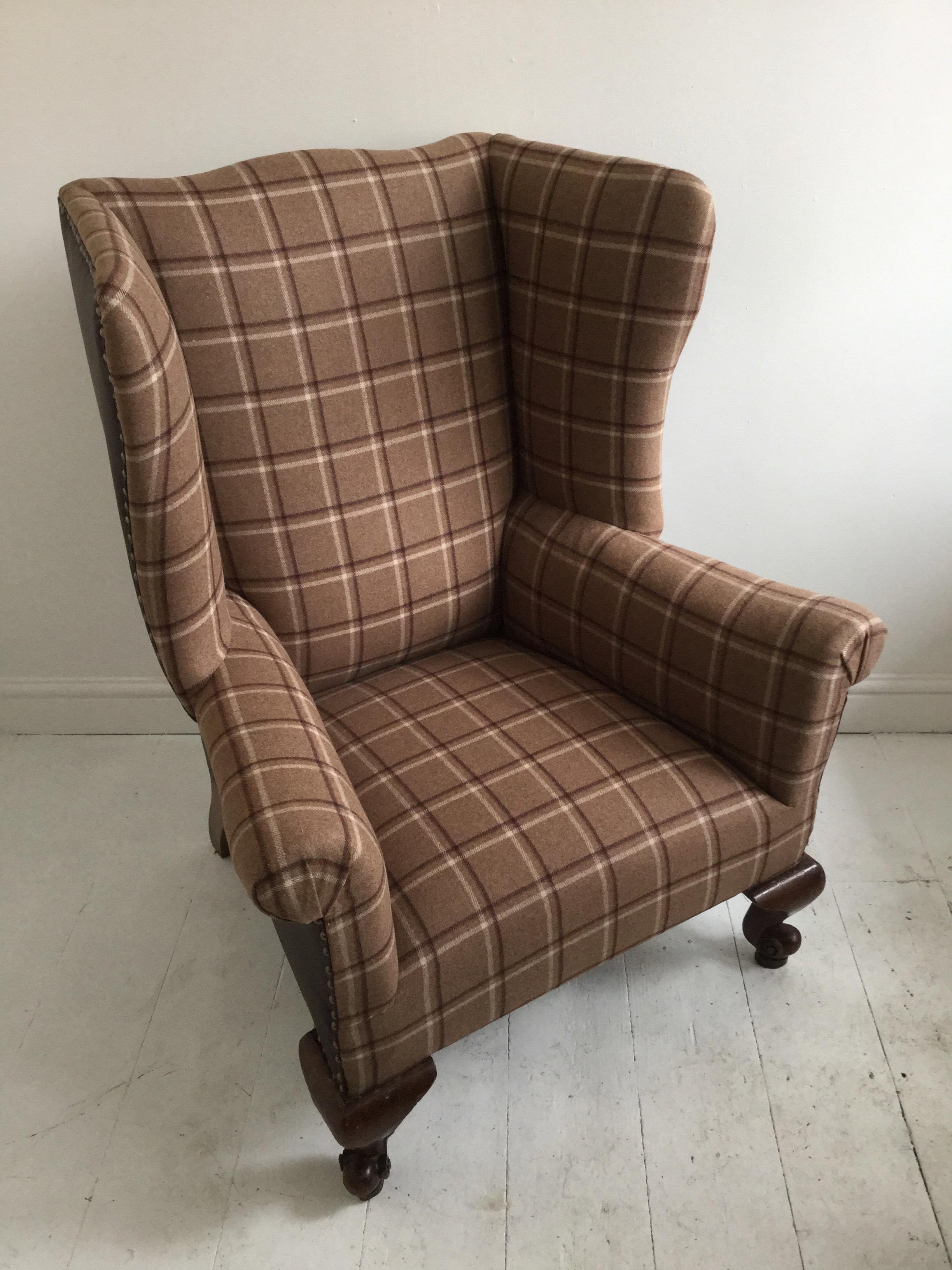 A great English Edwardian wingback or library armchair of generous proportion. It has been sympathetically upholstered in cognac leather and a plaid Scottish wool mix fabric. It has a Country gentleman's club house feel.
This chair has a firm seat,