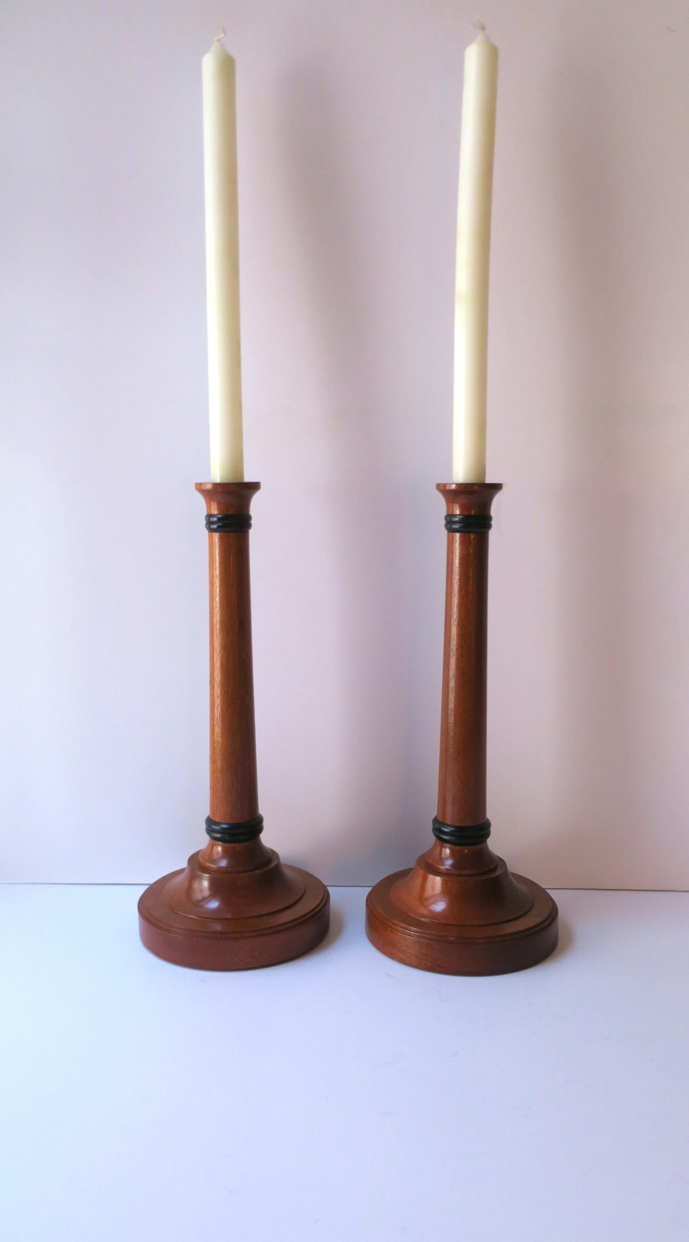 A pair of English hand-made wood candlesticks holders in a rich brown hue with black detail at top and bottom, circa late-20th century, England. Pair appears to have never been use. A great set for a dining table, fireplace mantel, etc. Marked 'hand
