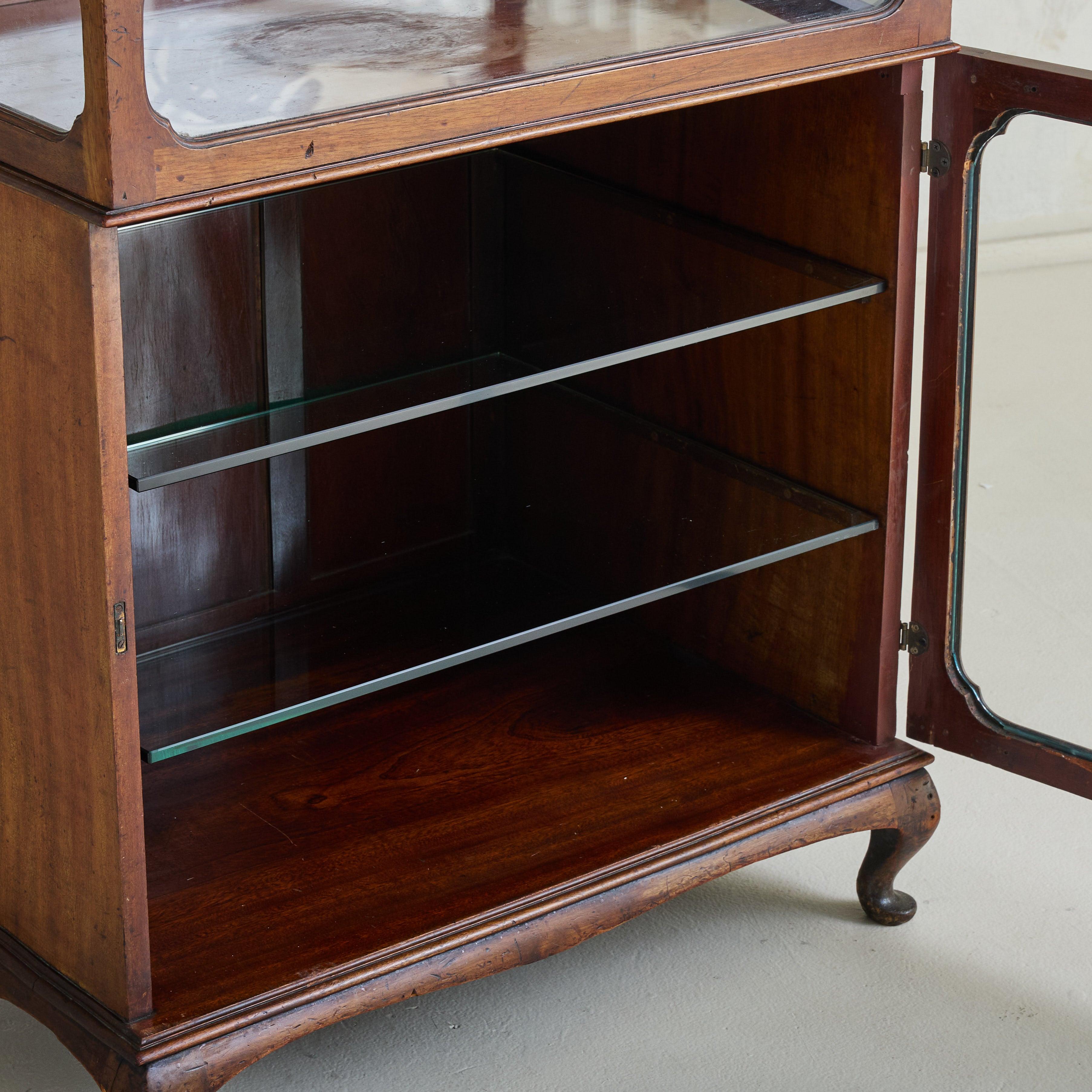 A refined 19th-century English display cabinet crafted from rich, solid wood. The cabinet features a rectangular form with bevelled glass panels on all sides, allowing for an unobstructed view of its two-shelf interior. Opening from both the top and