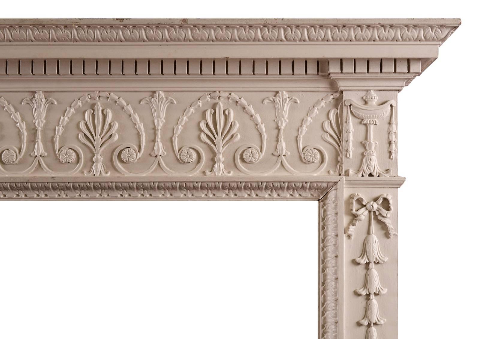 A finely carved pine George III style fireplace. The frieze with recurring palmette and bellflowers throughout, with classical urns to end blocks. The jambs with tied ribbons and belldrops. The shelf with dentils and acanthus leaves. English, 20th