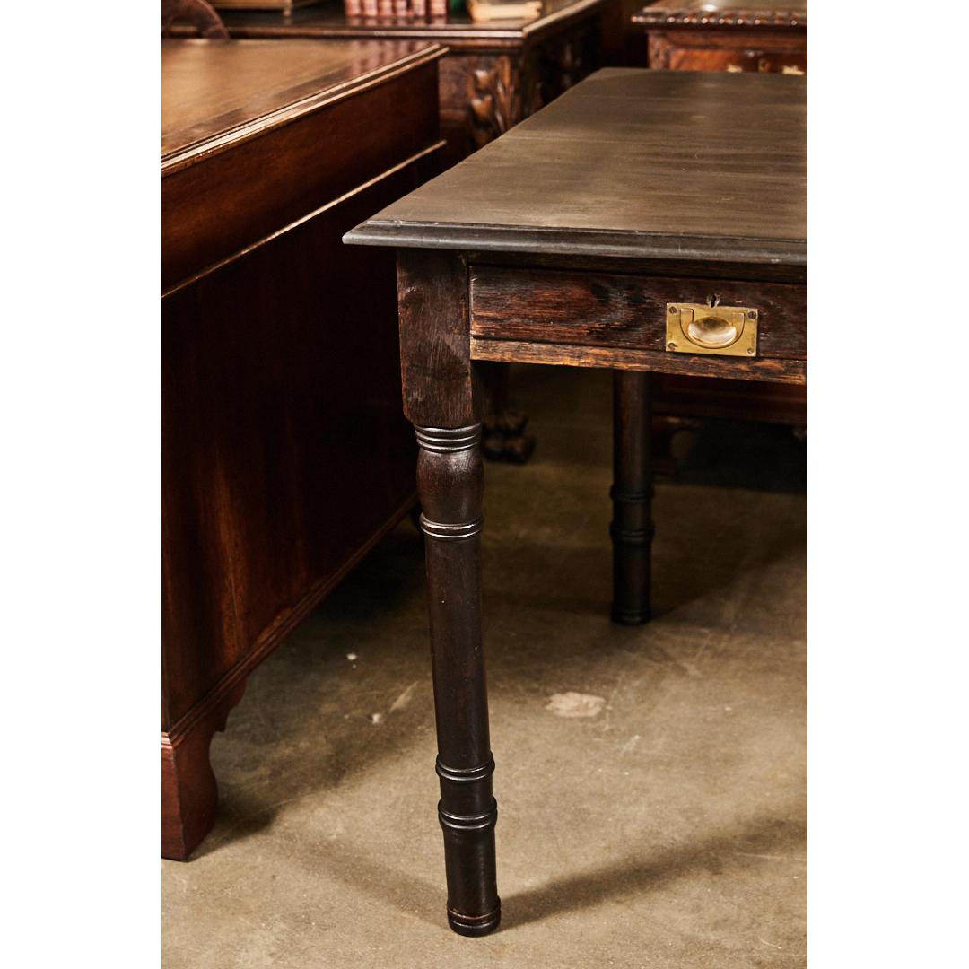 This impressive English writing table has three drawers with brass drawer pulls. The piece is made from oak and has four nicely piece turned legs. The piece has an ebony finish on the top.
 