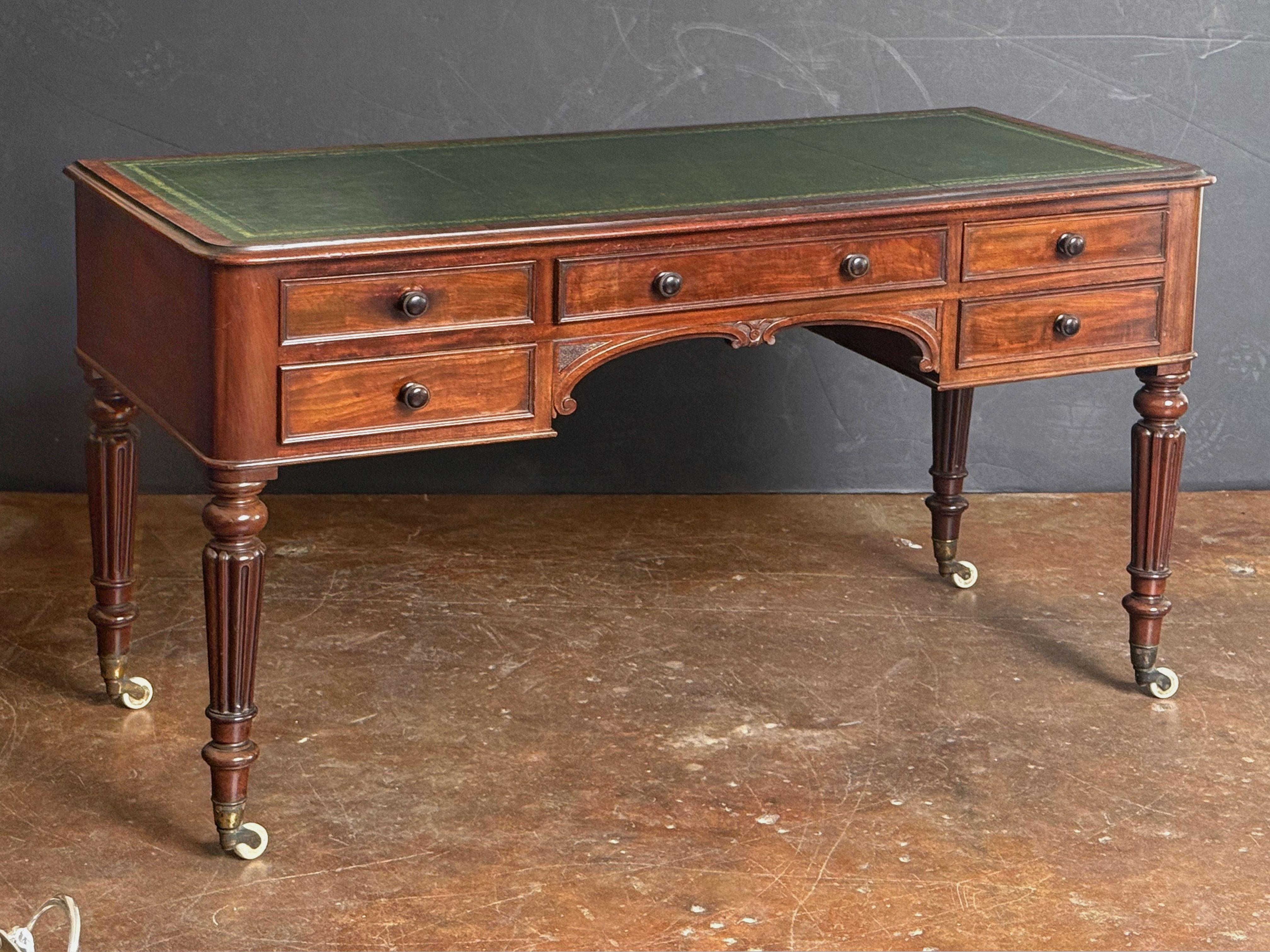 A fine English writing table or desk of mahogany from the 19th century, in the William IV style, from the celebrated English design company, Heal’s of London.

Featuring an inset embossed green leather top over a frieze of five drawers - each drawer