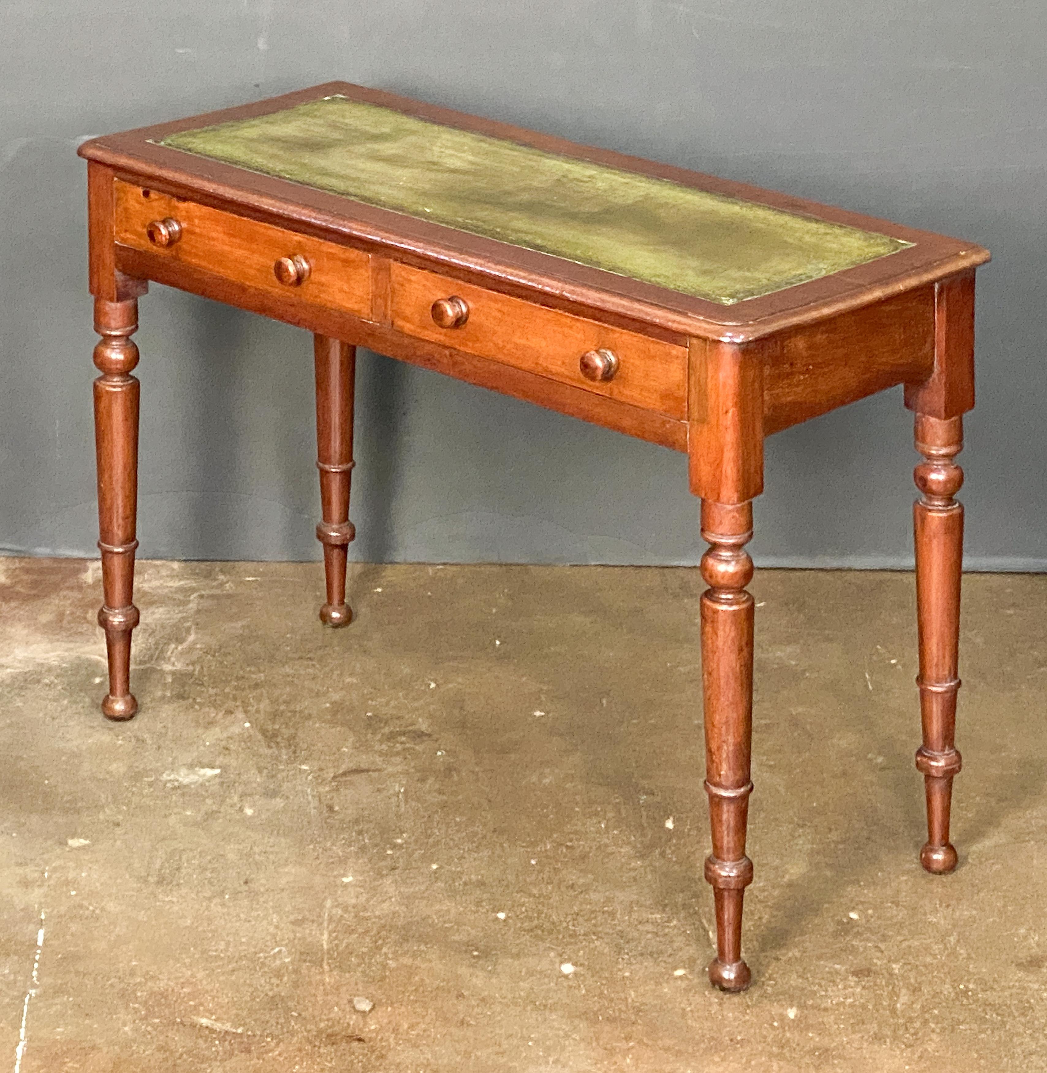 A fine English writing table or console desk of mahogany from England, featuring an inset embossed green leather top over a frieze of two drawers - each drawer with knob pulls - and standing on turned legs 

Dimensions: H 29 in x W 41 in x D 18.25 in