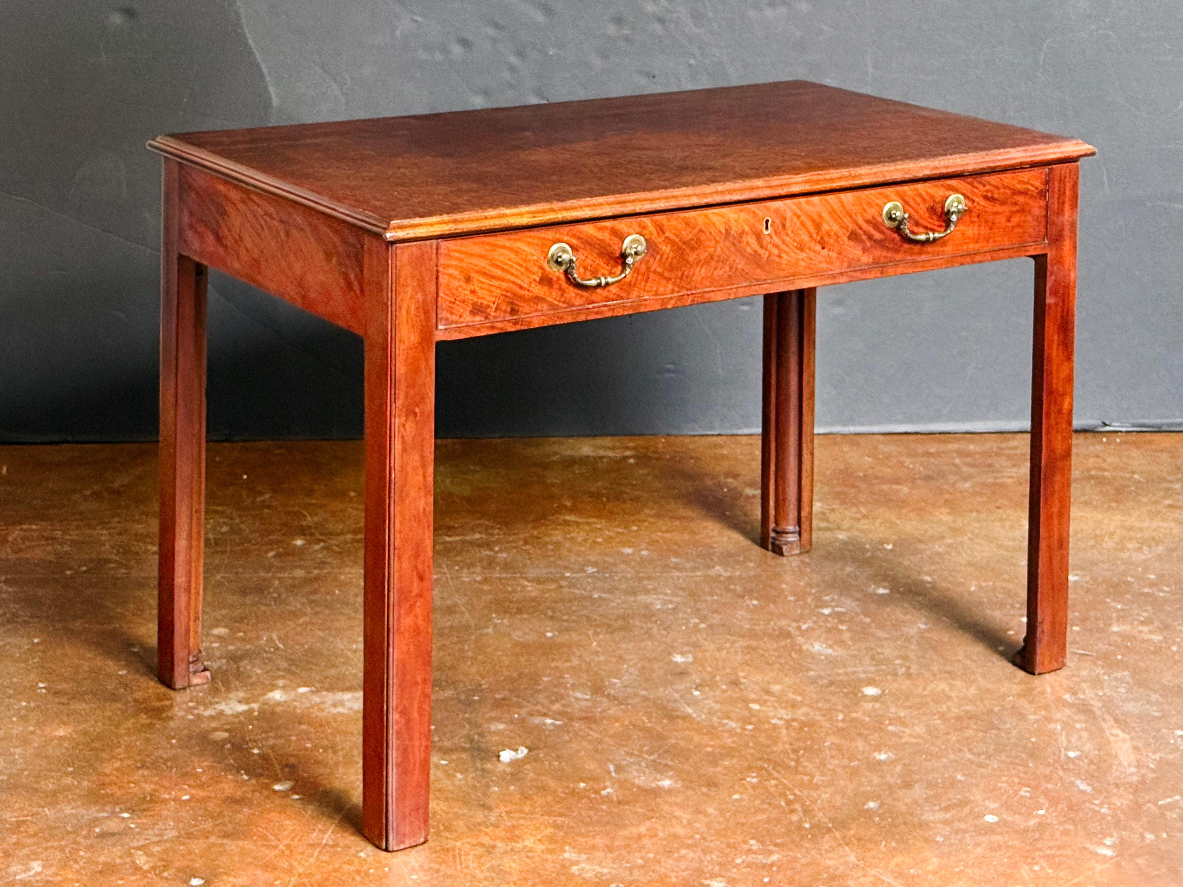 A fine and unusual English writing table or desk of mahogany from the Georgian period, featuring a moulded rectangular top over a frieze showing two faux drawer fronts with brass swan pulls, the ingeniously designed frieze pulls out showing a