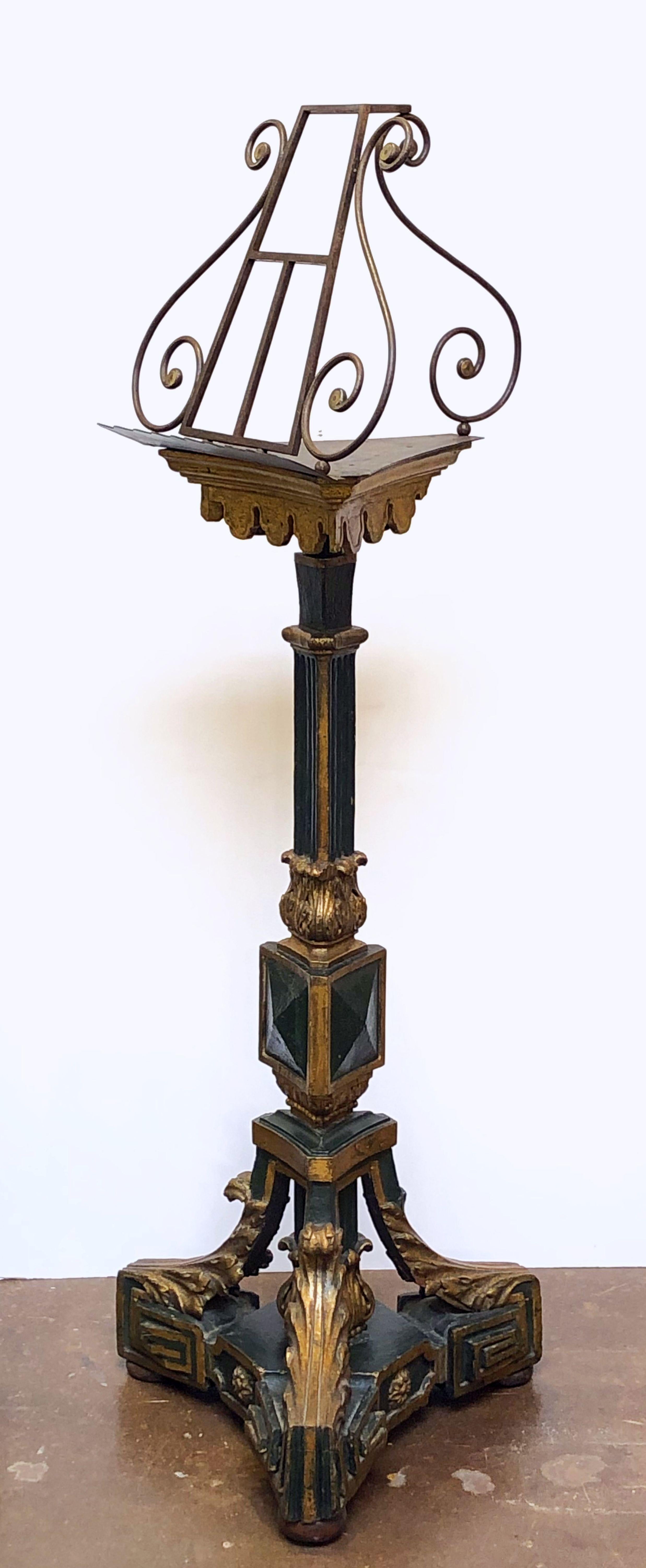 A fine English standing lectern or music stand, featuring a lyre-shaped scroll-work top attached to a pedestal column of painted carved wood with gilt accents and decorative Greek Key and acanthus leaf flourishes, on a tripod base. Measures: H 69 ½.