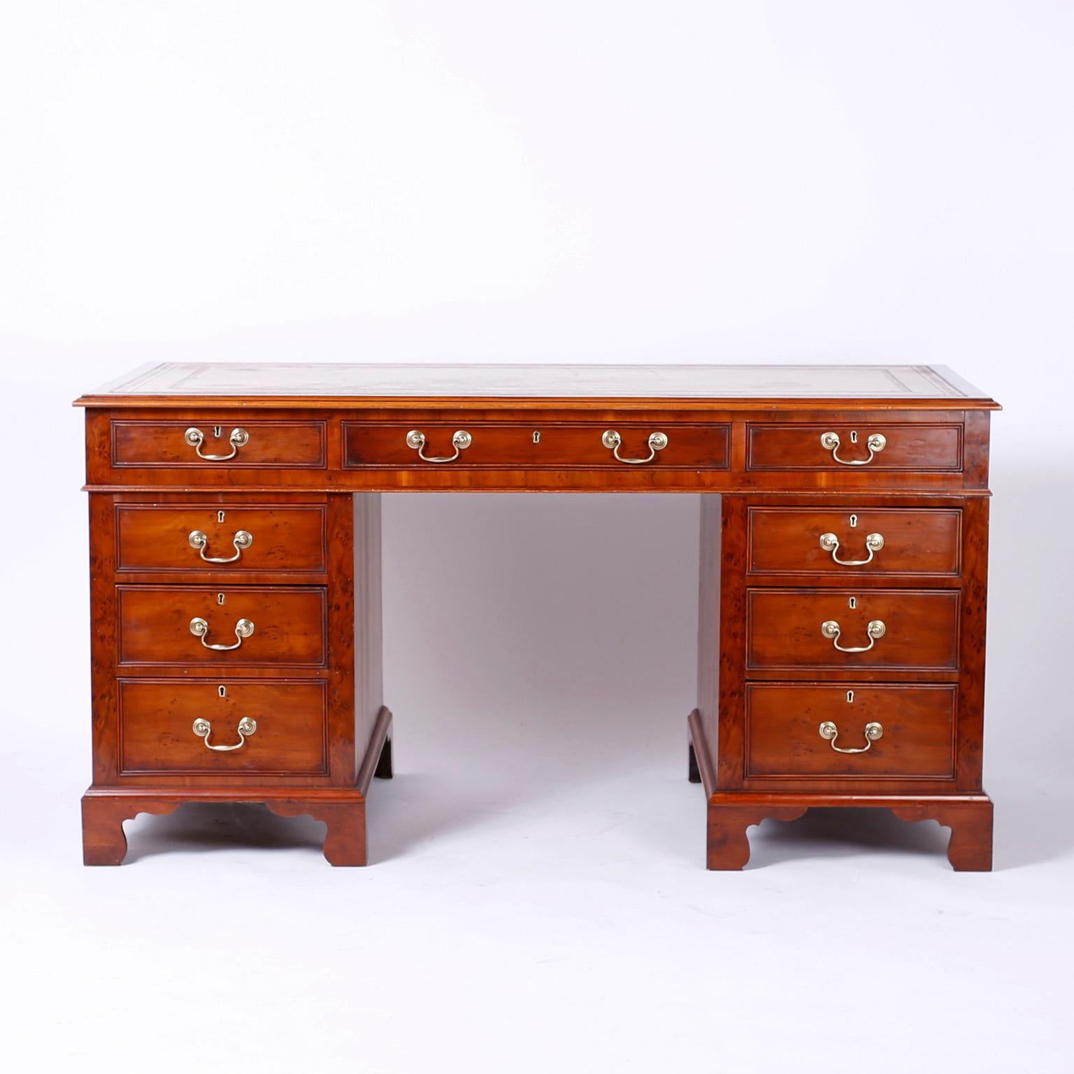 Antique 19th century English desk crafted in well grain and burled yew wood, having the original tooled mustard leather top now aged to perfection, nine drawers in front, finished back and set on classic bracket feet. 

Kneehole width 24 inches.