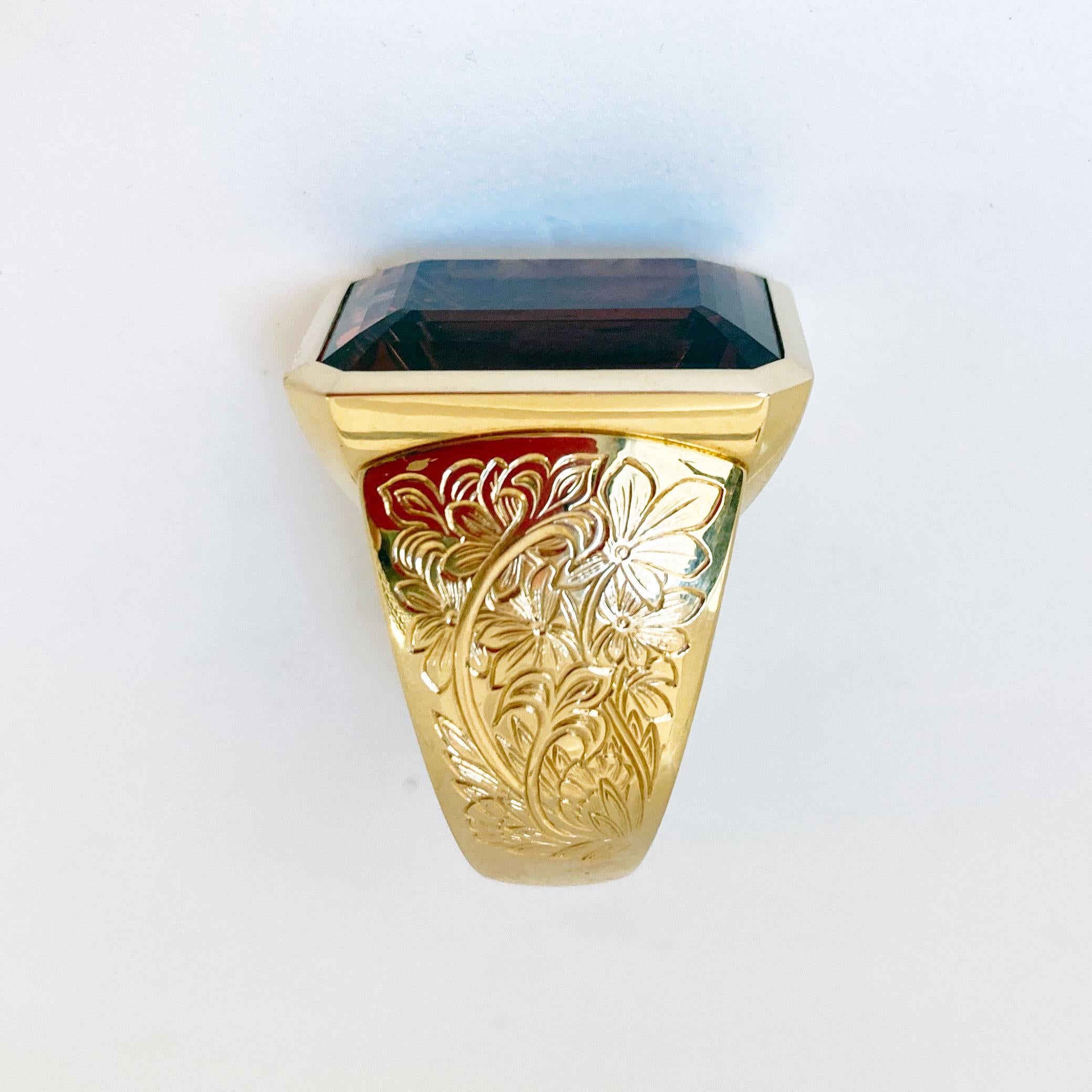 A very solid 18 Kt Rose Gold  Cocktail Ring showing an emerald cut dusty pink bezel set Tourmaline of 28.51 ct.
The shoulders are engraved with an intricate floral design. 
Stone dimensions  21.3 x 15.2 mm.
Total Weight 44.6 gr.
Size 15 / 7 . The