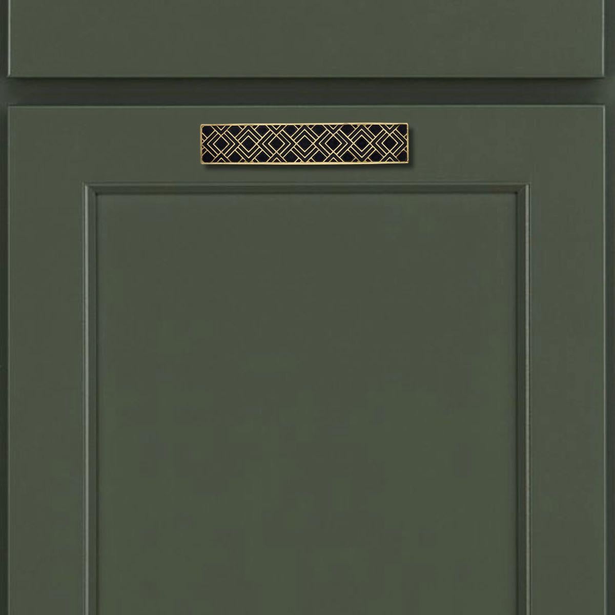Cette tirette de meuble rectangulaire est fabriquée en laiton massif à l'aide d'un procédé de gravure traditionnel. Le motif précis s'inspire de l'ornementation Art déco, avec des lignes géométriques soigneusement remplies à la main de résine noire.