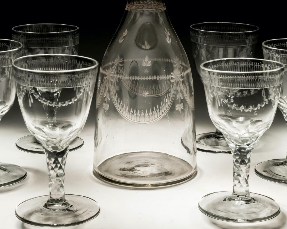 A Continental magnum decanter of tapered shape with ten matching large wine glasses all engraved with swags.

Portugal, circa 1785.

Measures: height: 35 cm (13 3/4