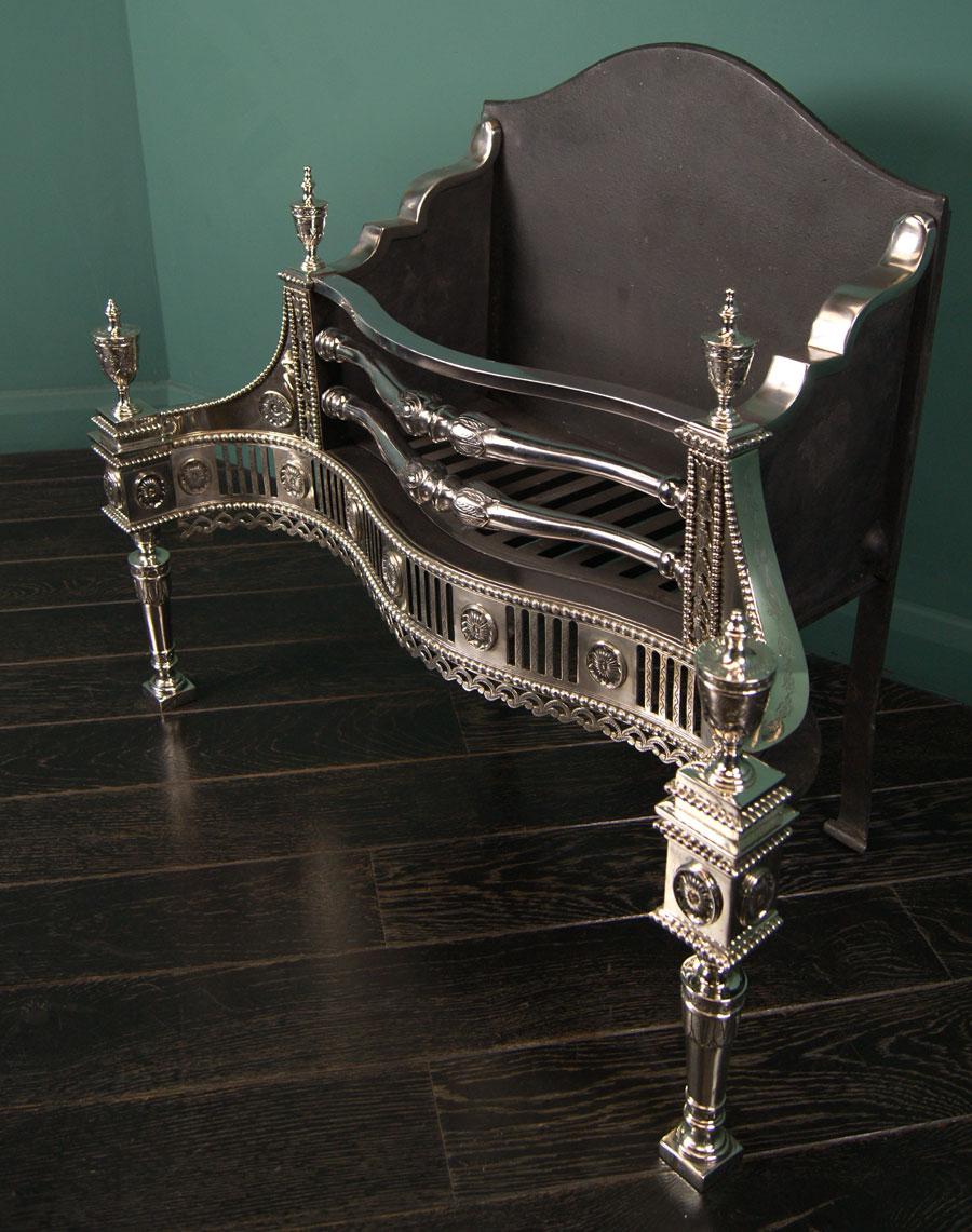 A highly decorative engraved German silver serpentine fire grate with central acanthus detailing to fire bars, flanked by harebell columns, outswept wings over a fluted pierced frieze interspersed with oval patera within beaded boarders. Column legs