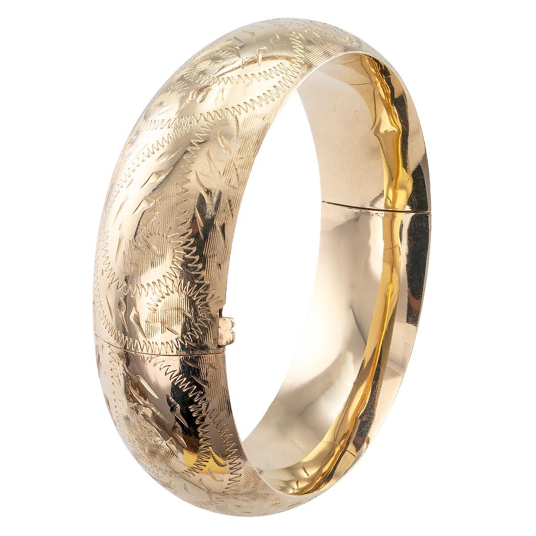 Engraved gold bangle bracelet circa 1980. The slightly domed and hinged design is lavishly hand engraved all around, crafted in 14-karat yellow gold with maker’s marks for Manart. We love the width of this bangle and that the rich pattern of the