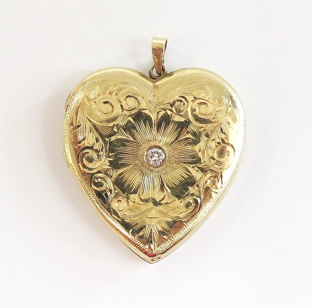 There's beautiful detail and hand engraved curls, swirls, and a flower on the front of this lovely vintage locket with a center bezel set 0.05 Carat
Diamond. The back has an example of the long lost art of hand engraved monograms. The intertwining