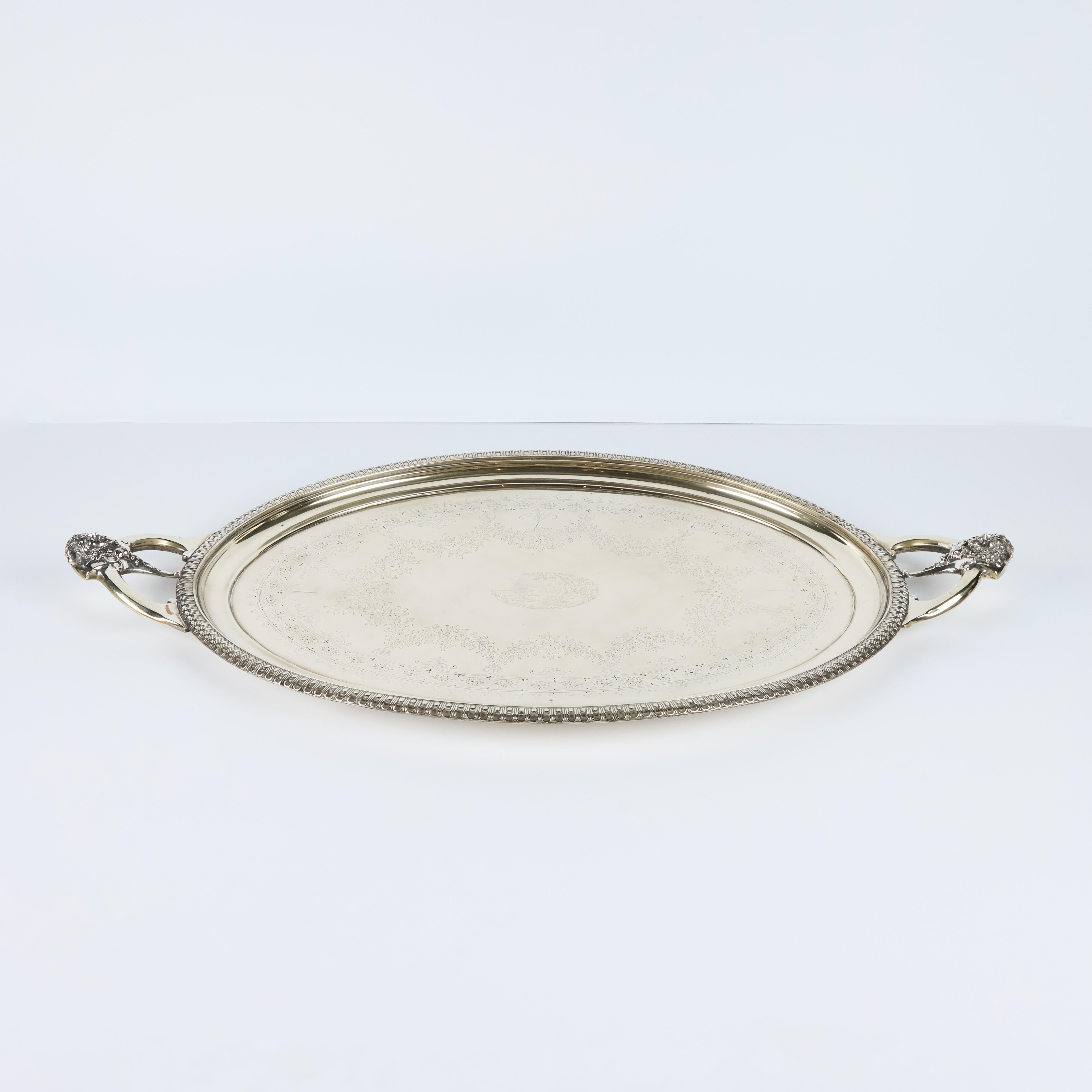 Bandeja de servir grande, grabada a mano, con detalles y bañada en plata, con asas en forma de cabeza de sátiro.