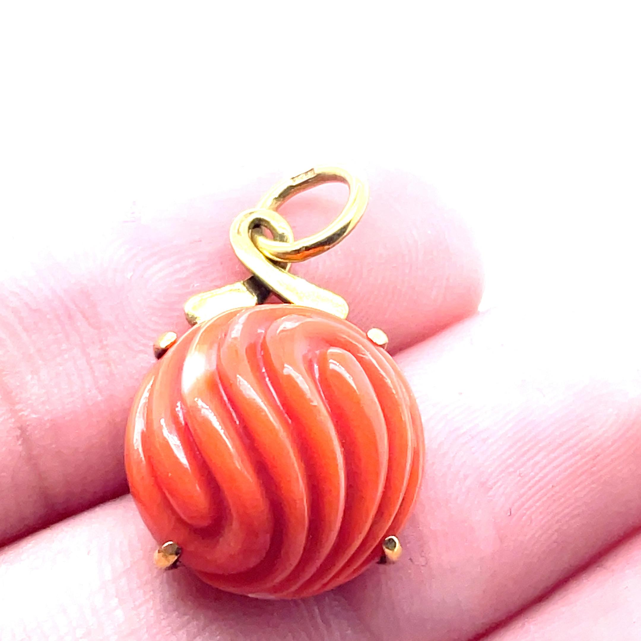 Caratterizzato da uno splendido corallo rotondo cabochon, questo ciondolo irradia un'accattivante tonalità rosso-arancio che emana calore e charme. 

L'intricata incisione intorno alla pietra aggiunge un tocco di raffinatezza, rendendola un perfetto